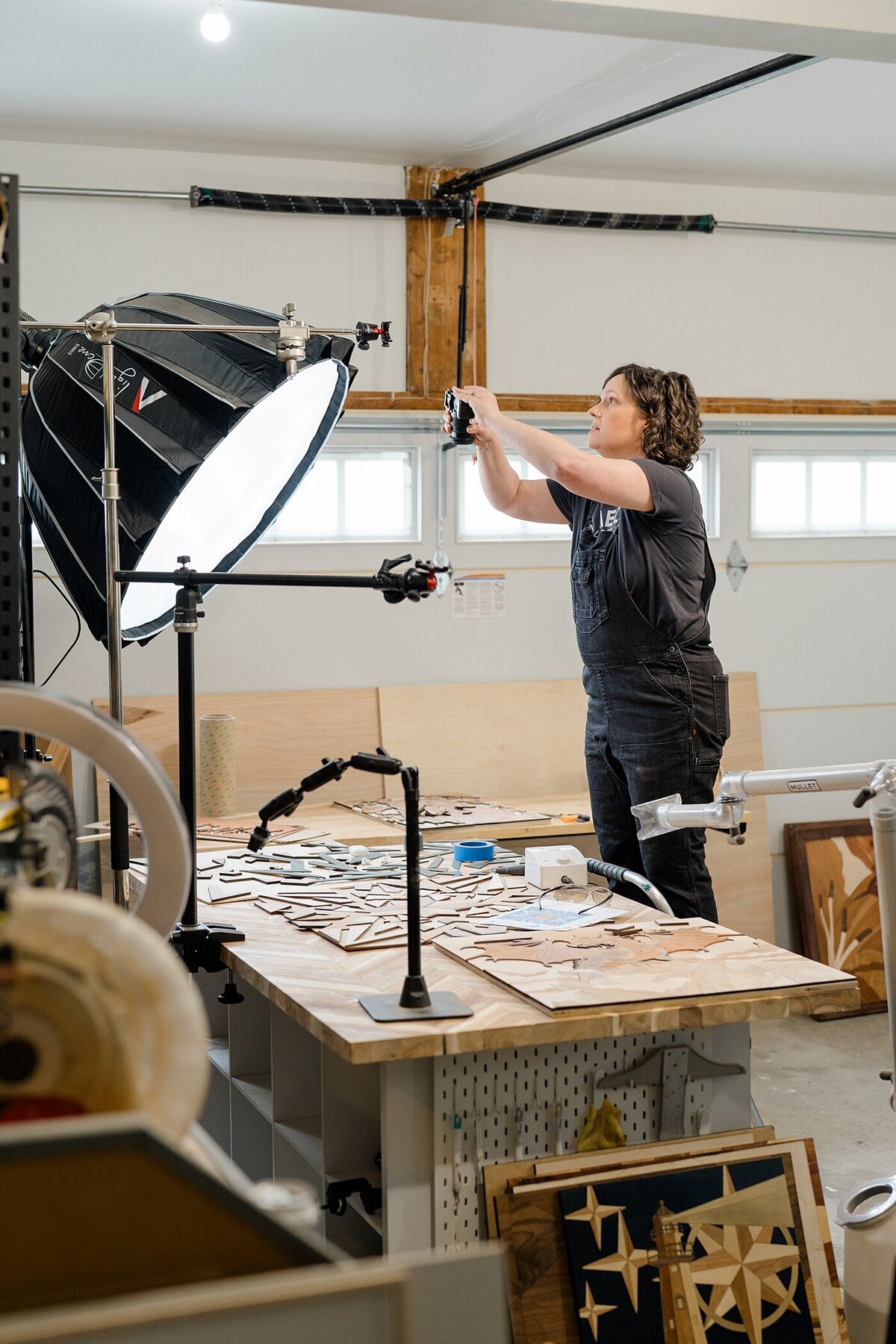 Columbus photographer photographs creative business owner with woman taking pictures on her products on her phone in a her woodworking shop