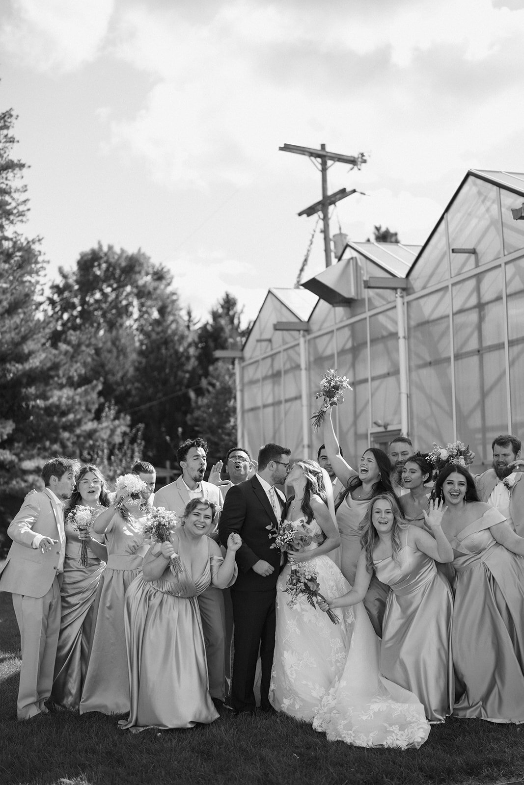 Bridal party cheering and celebrating together with the Ivy House greenhouse behind them.