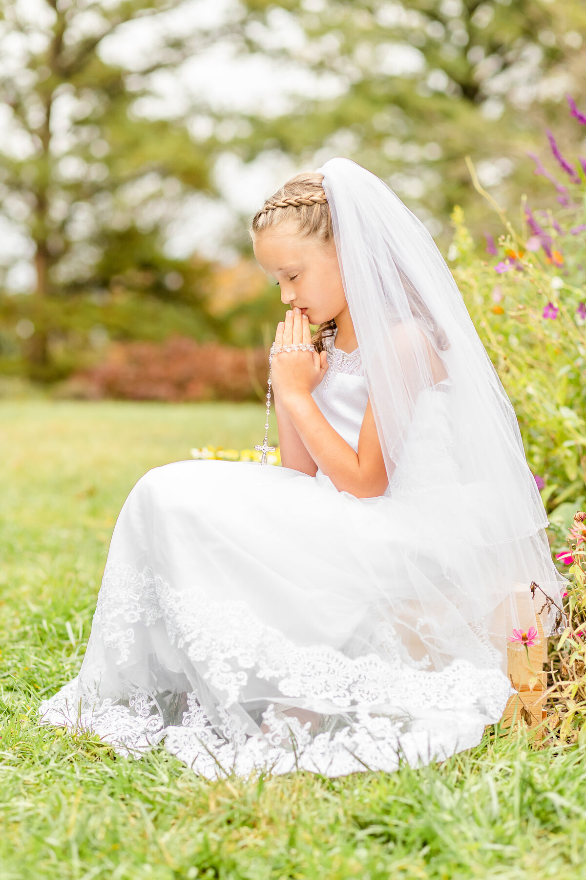 First communion girl praying in flowers