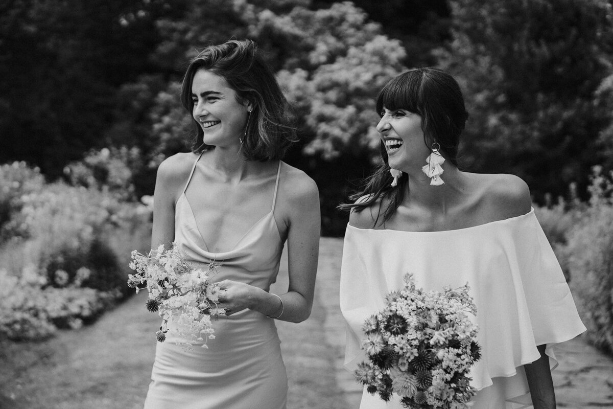 bruid met bruidsmeisje, lachend, bloemen
