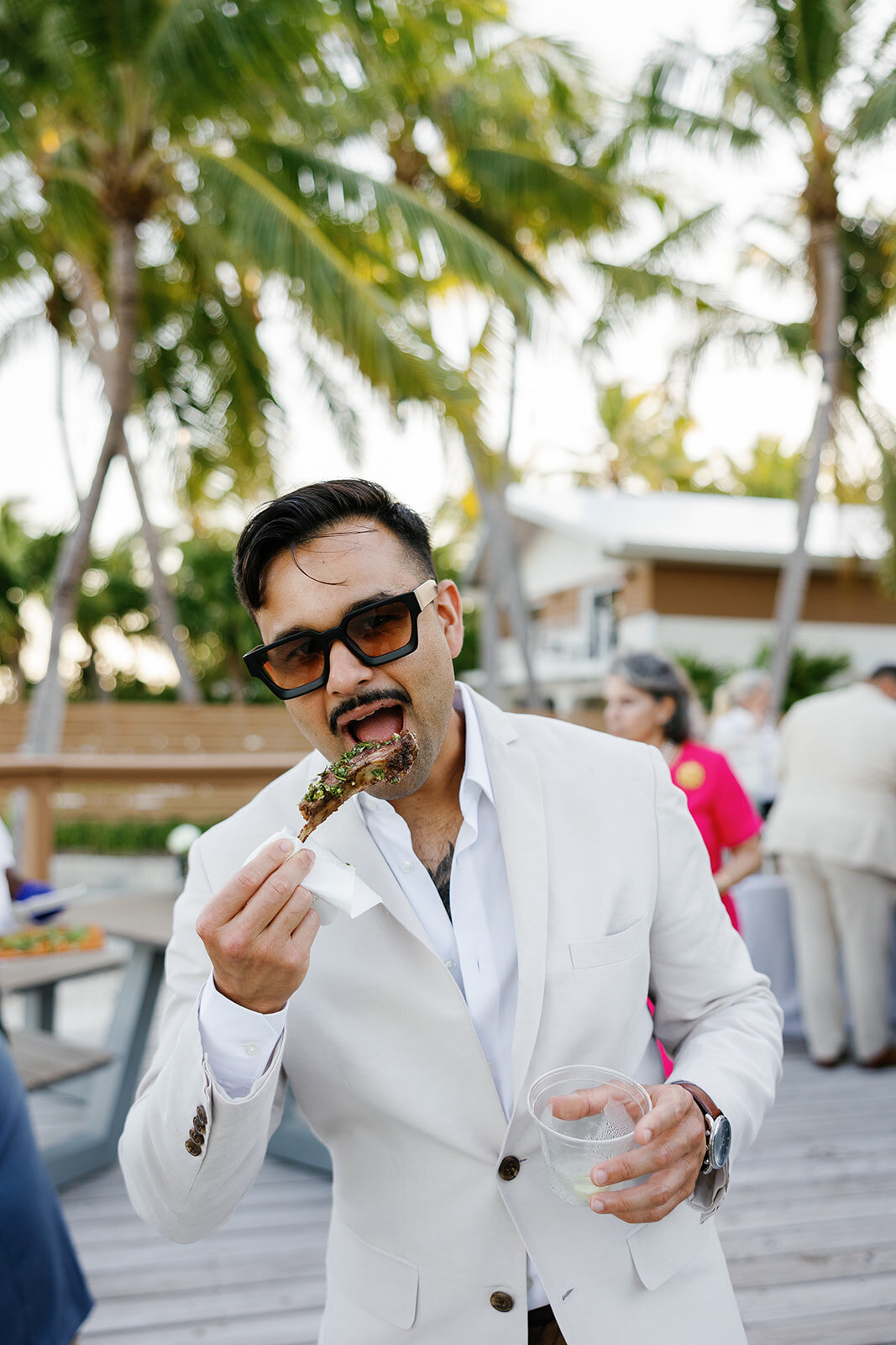 Elegant wedding guest in sunglasses sipping a drink at the Islamorada wedding reception.