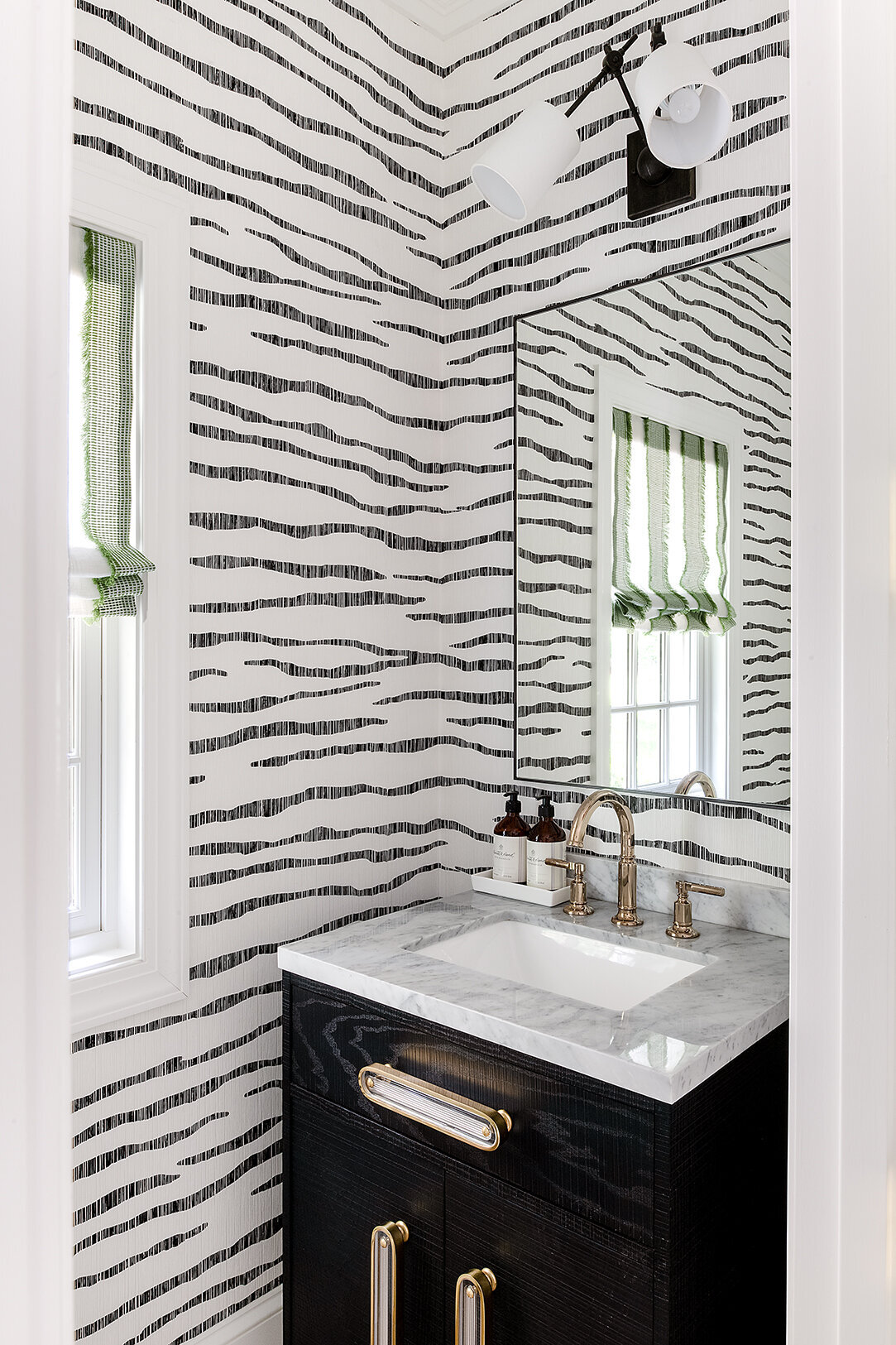 bathroom with black and white striped wallpaper, marble sink, and gold faucet