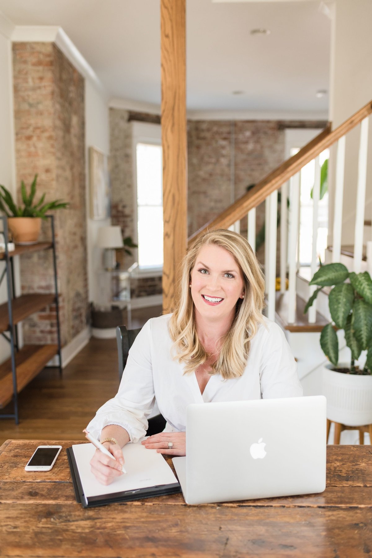 Nashville business owner sitting at wooden table with laptop and notebook