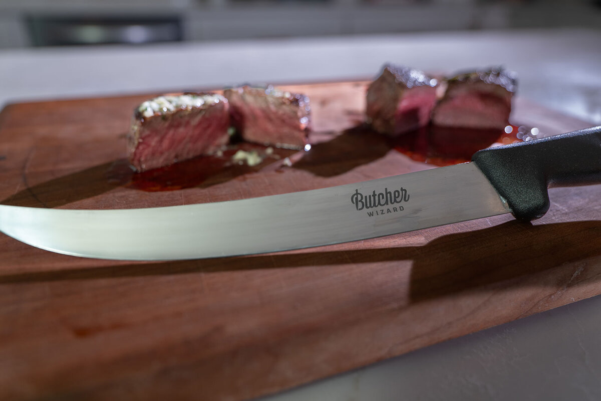 A knife sitting in front of cut steaks 