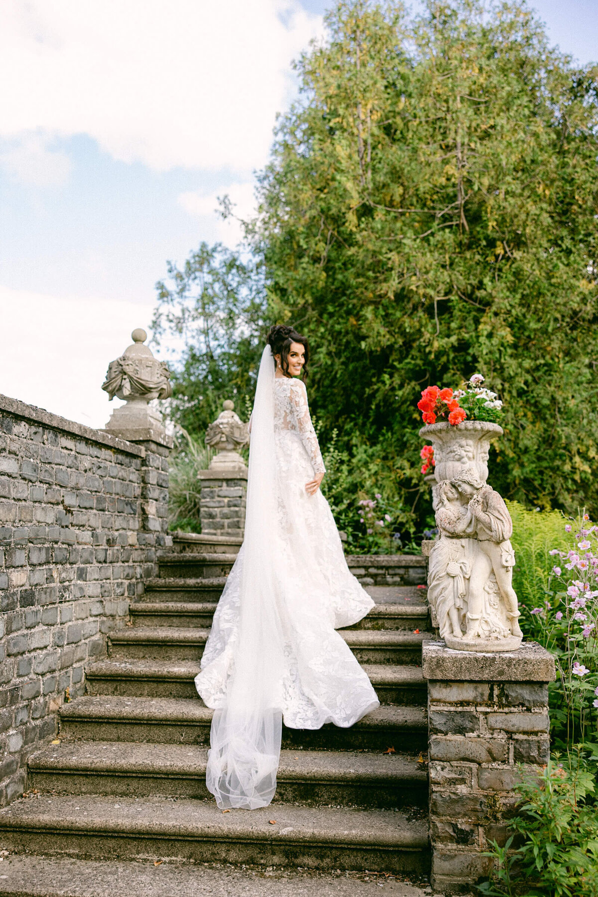 A wedding photo of a bride in her white dress walking up stone steps at Luttrellstown Castle