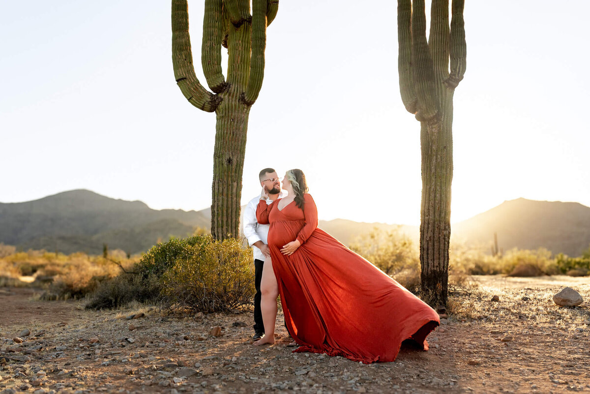 expecting parents standing amidst 2 large saguaros for stunning Arizona desert portrait