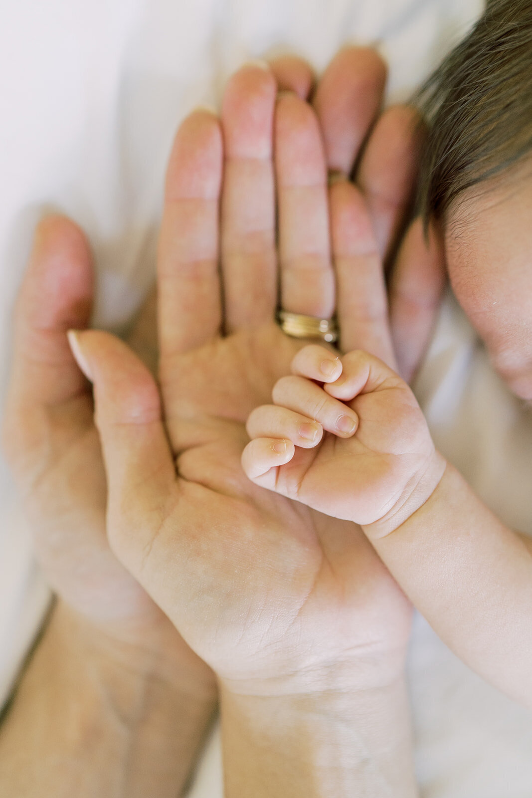 a newborn's hand rests on top of his mothers and fathers hands