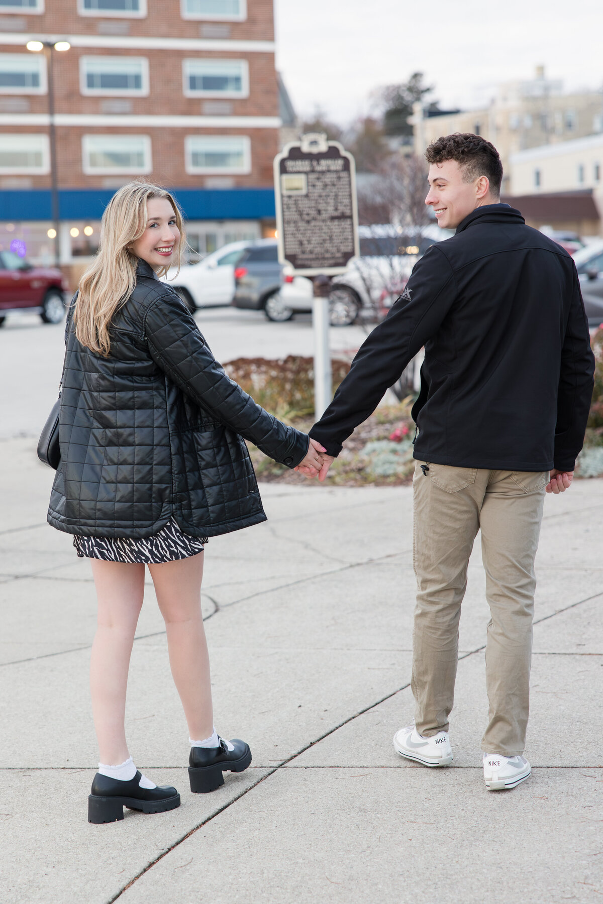 Engaged couple holding hands and walking away from the camera