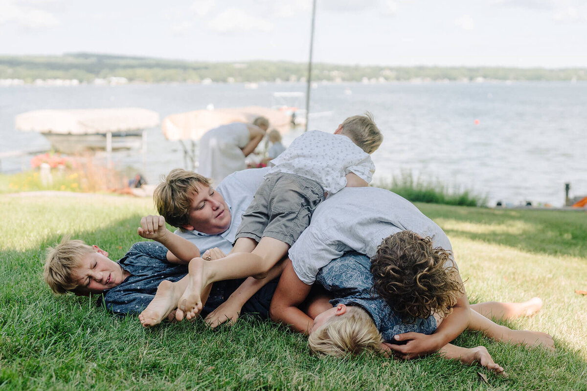 young boys lying in a pile on the grass at generational photoshoot in Finger Lakes, NY