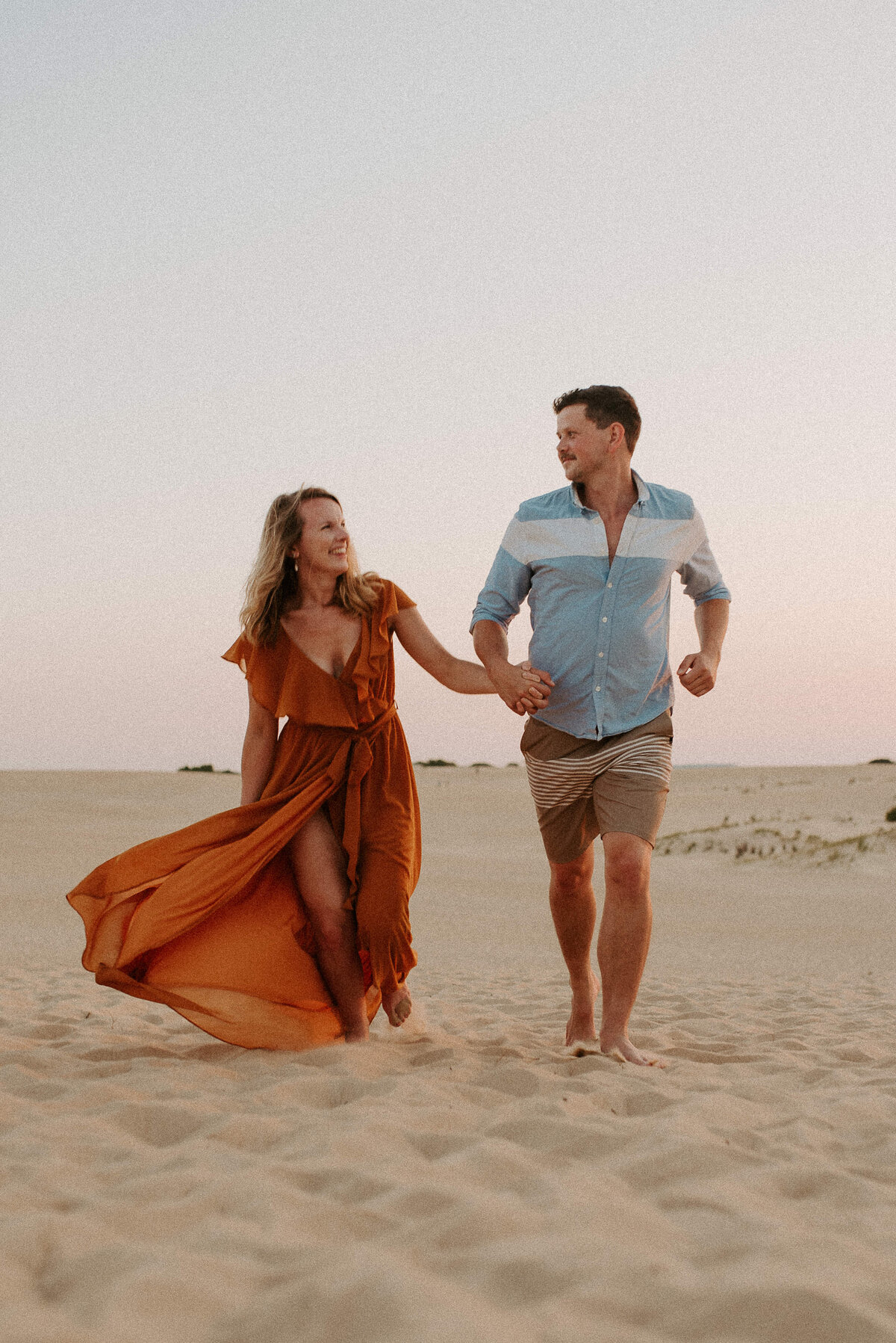 Running through the sands during an engagement session at Coral Pink Sand Dunes State Park in Kanab , Utah at sunset wearing a Baltic Born dress.