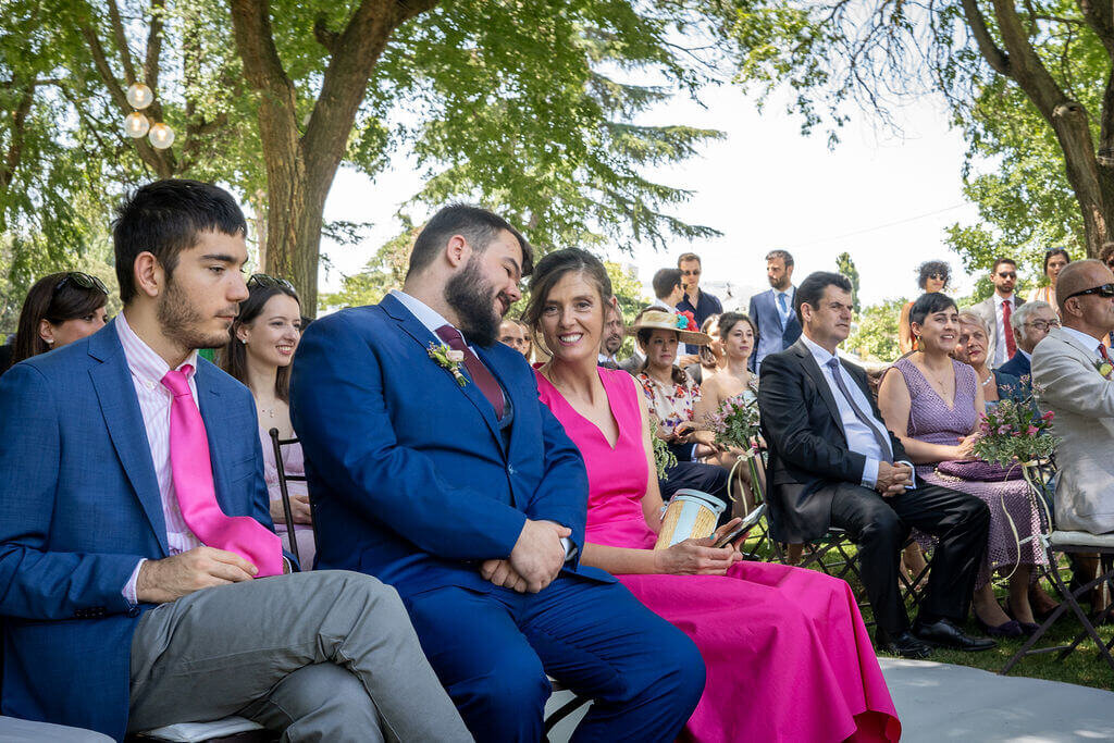 Woman in pink dress smiles at best man during wedding ceremony