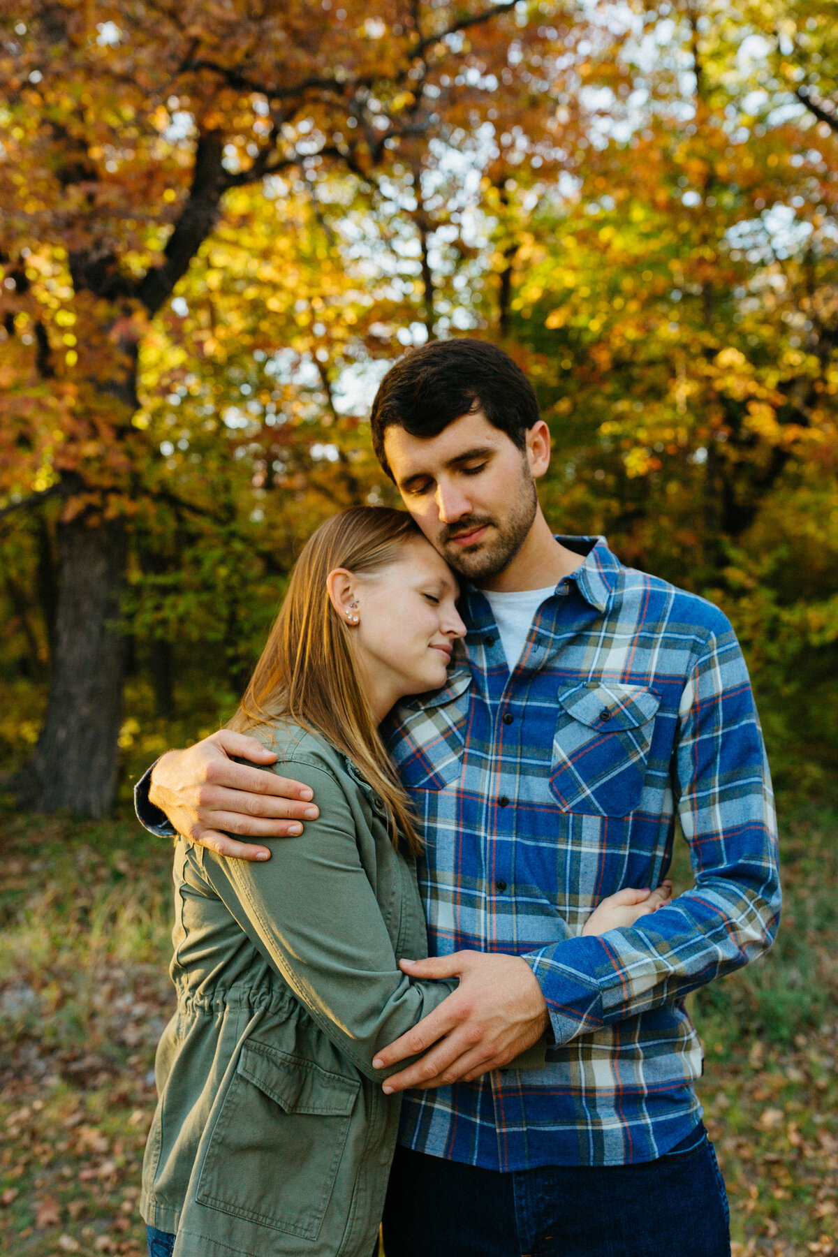 engaged-couple-hugging-by-fall-trees