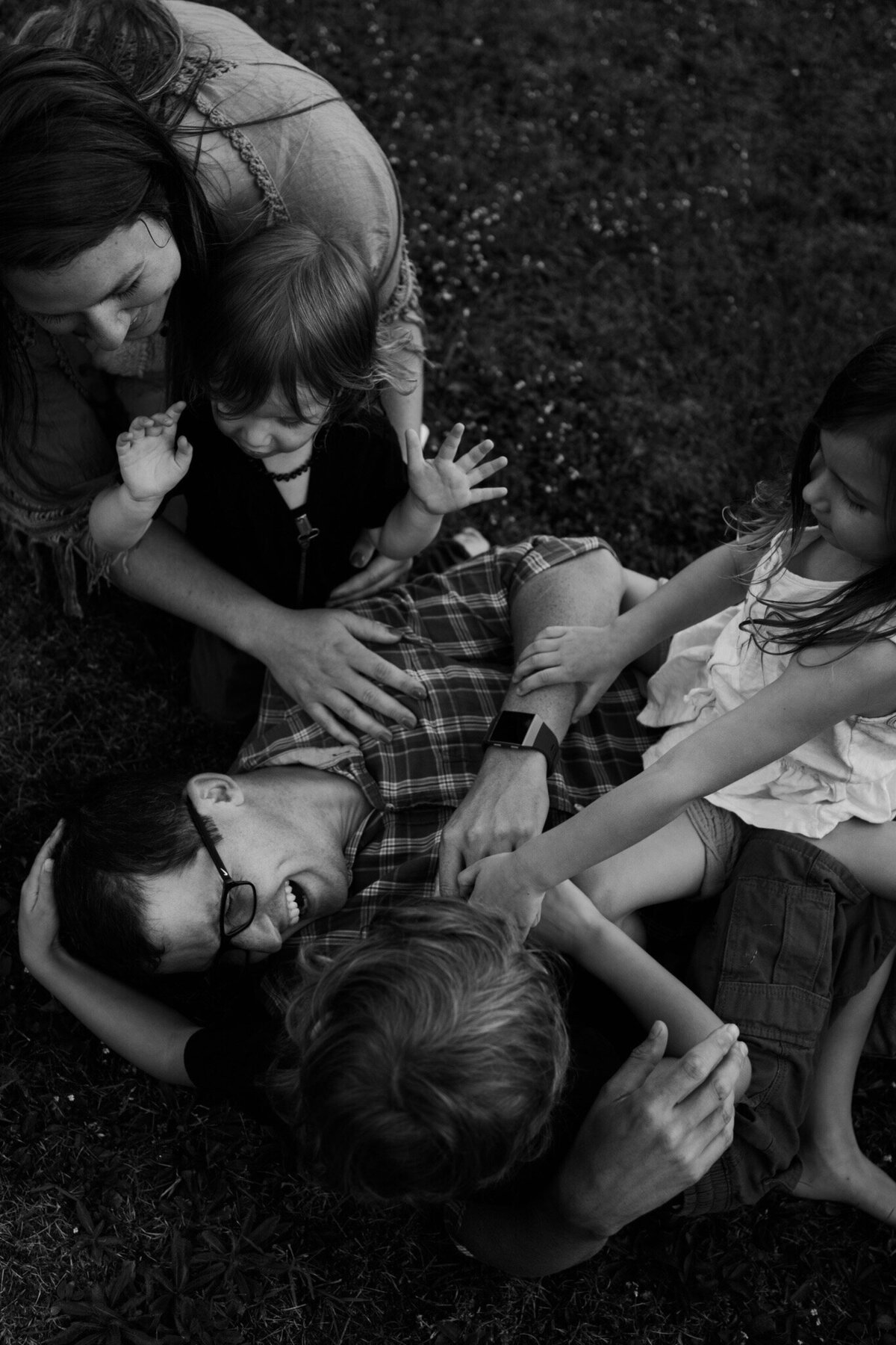 black and white image family laying on ground laughing