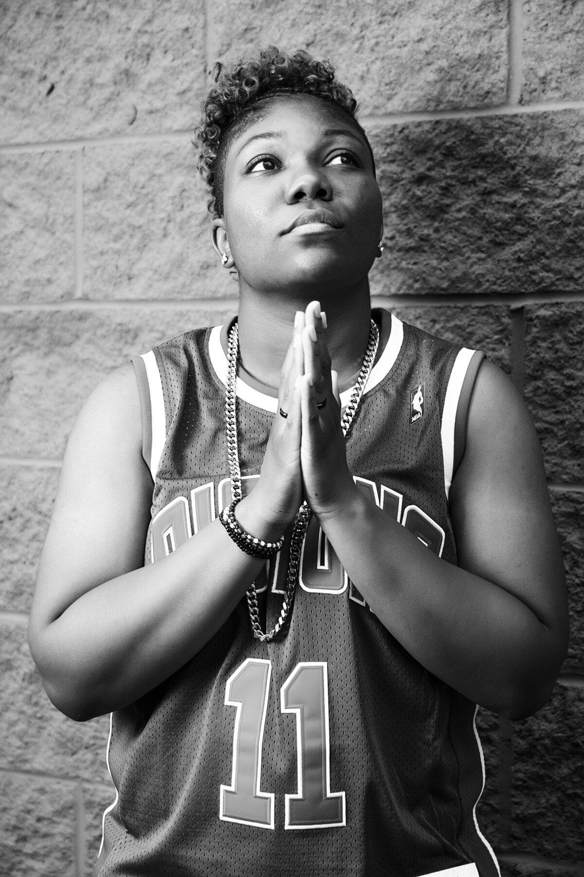 African American woman in Detroit Pistons jersey with praying hands