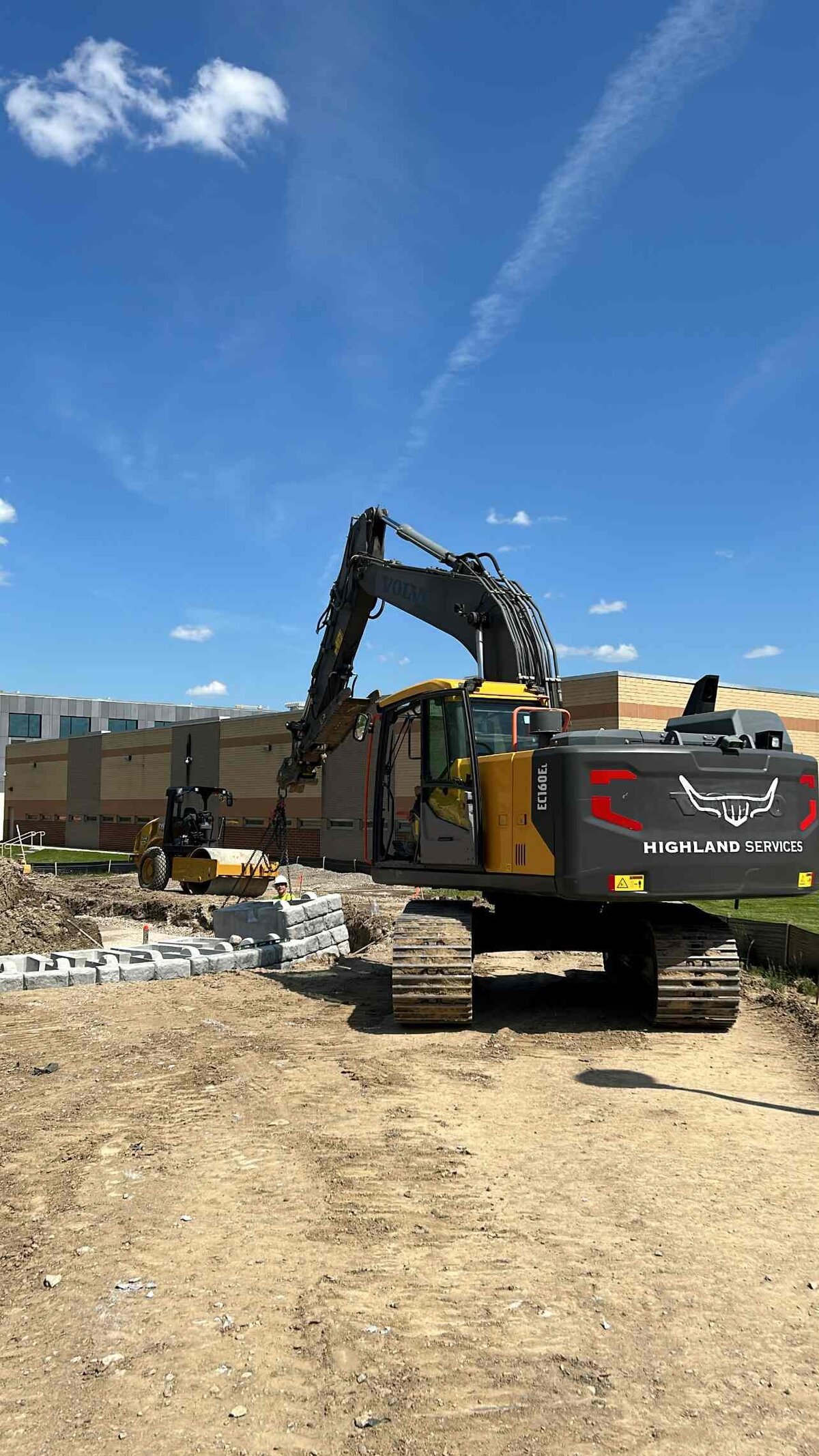 redi-rock-retaining-wall-placement-michigan-correctional-facility-highland-services-excavator