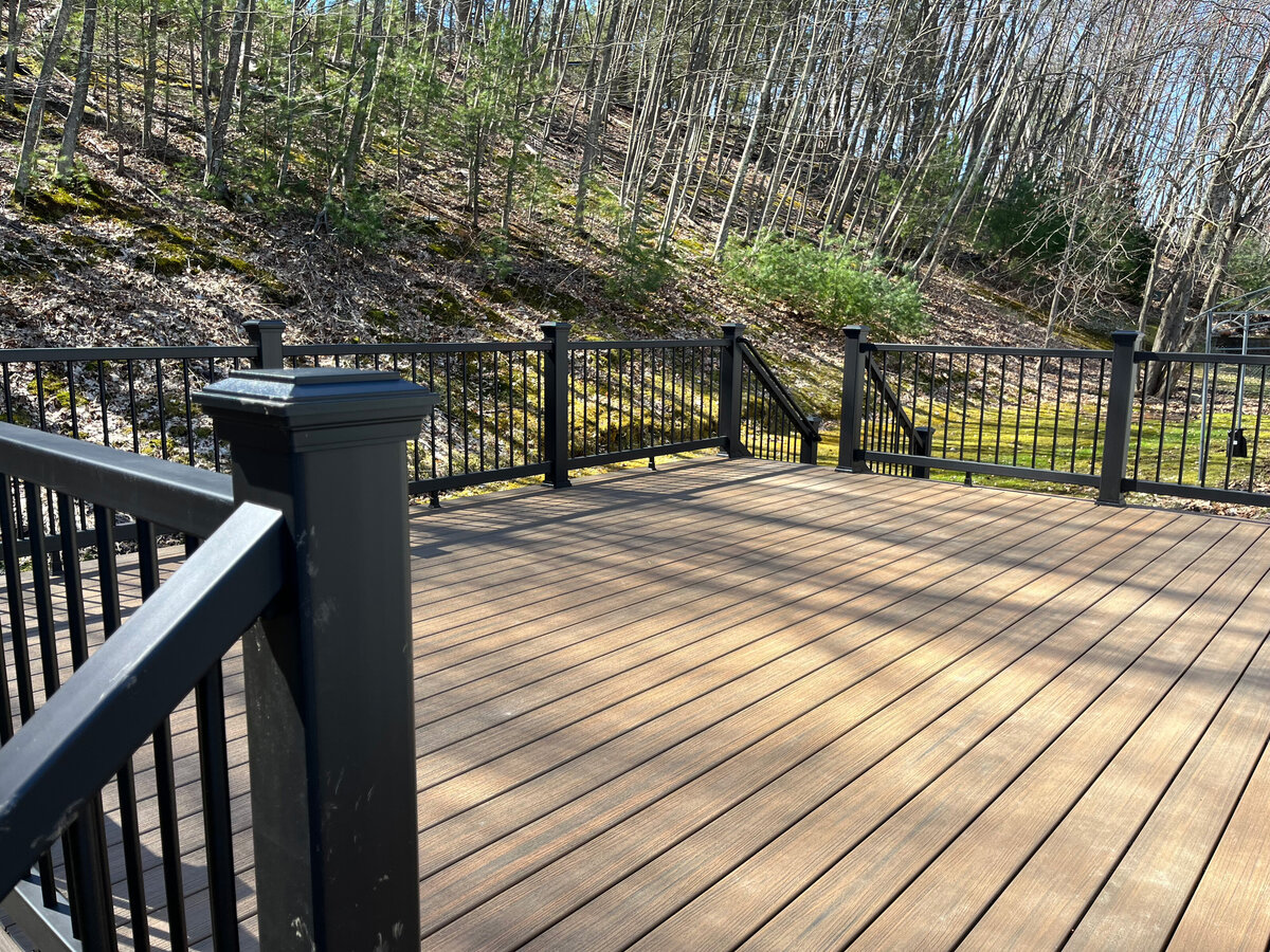 A dark natural wood looking composite deck with black railings built by a Holden MA Deck Contractor