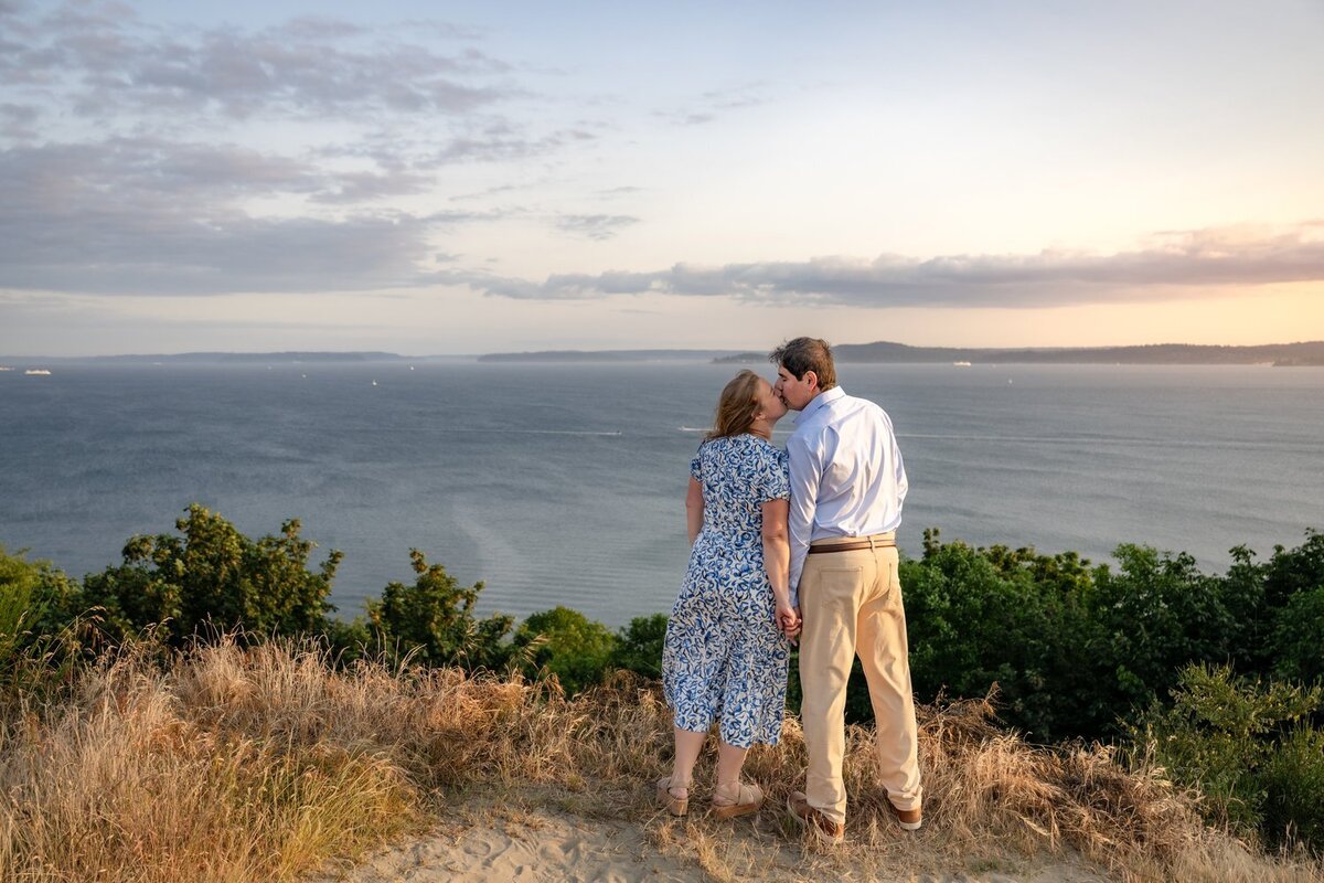 couple kiss at sunset on discover park seattle bluff