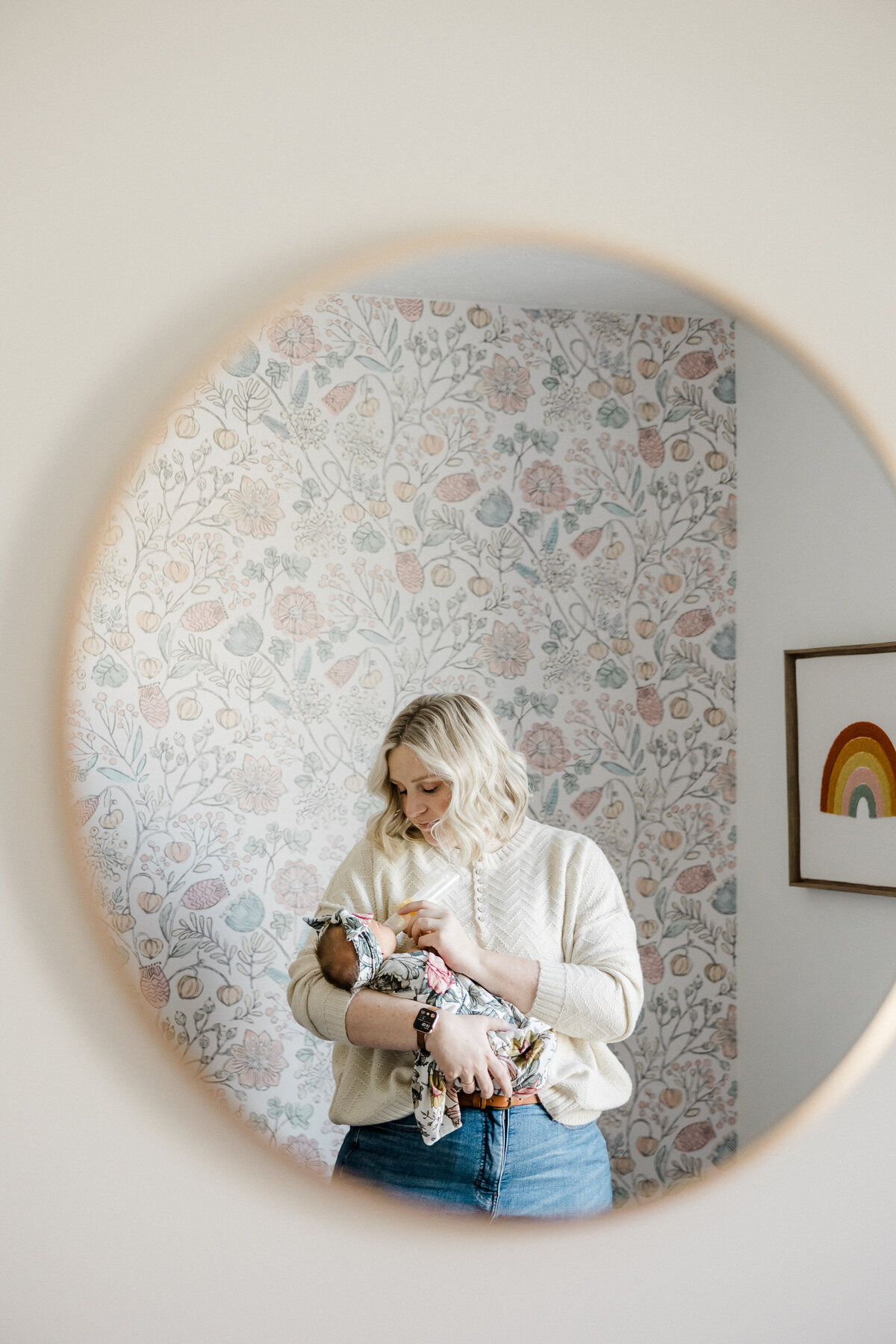 reflection in the mirror of mom holding newborn baby