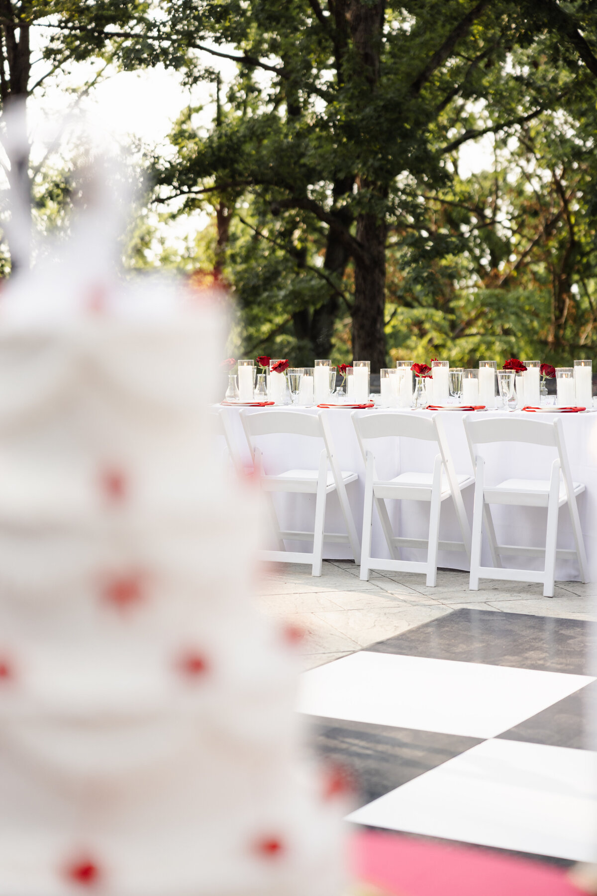 Outdoor wedding reception table with red roses and white candles