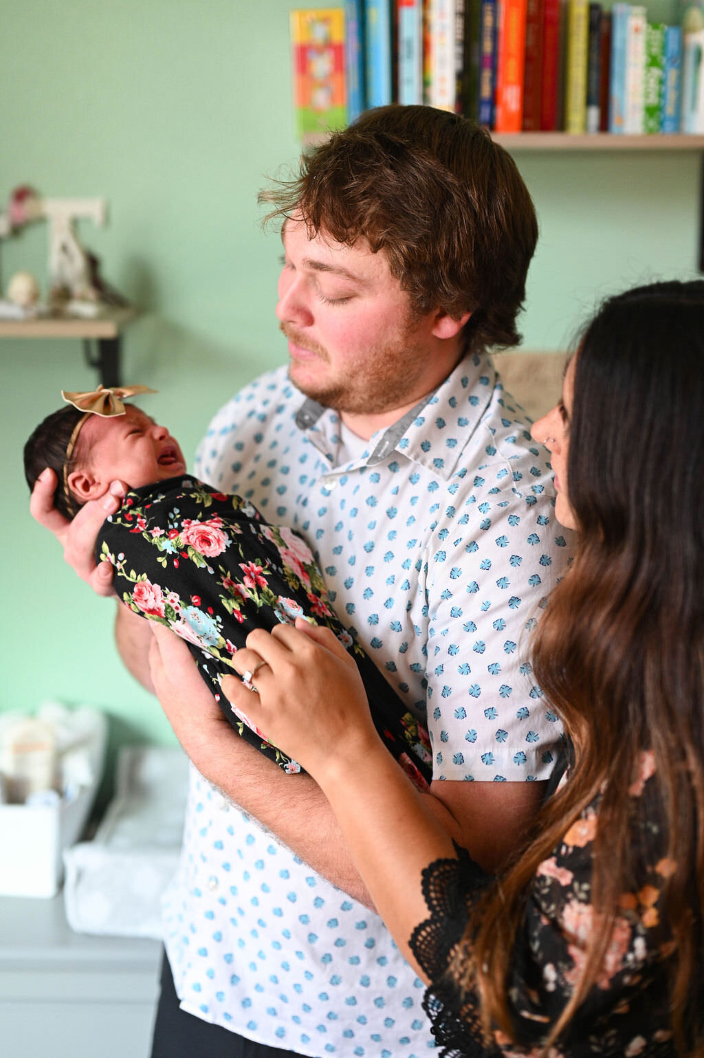 A dad holding a newborn as she cries.