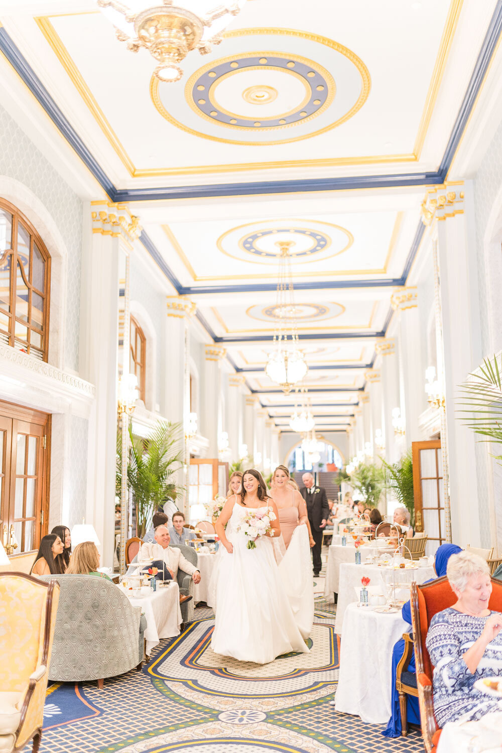 Bride walking with bridesmaid through grand hotel hallway