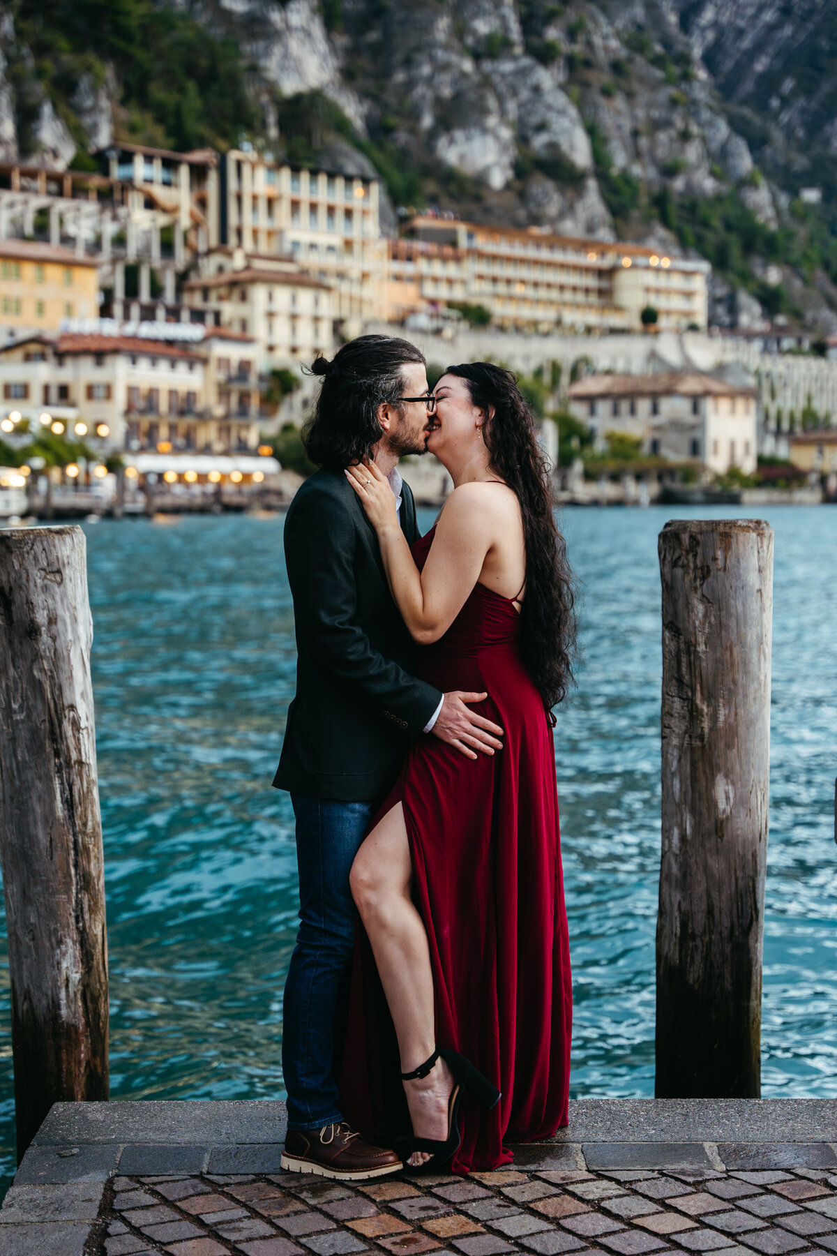 Lake Garda honeymoon session couple walking by the water with city lights in the background