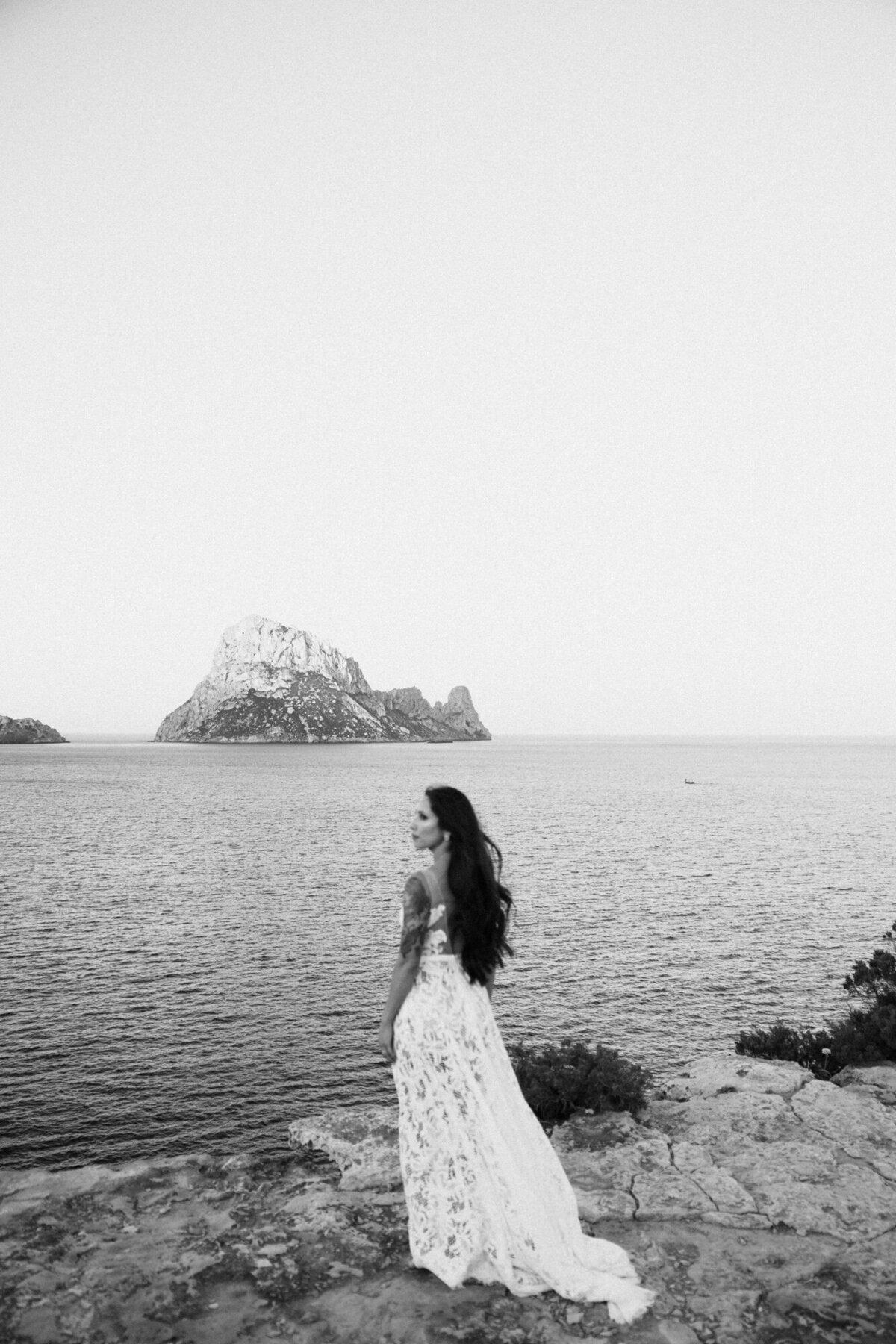 Bride is standing near the cliffs and  looking over te sea with Es Vedra in the background for wedding photography