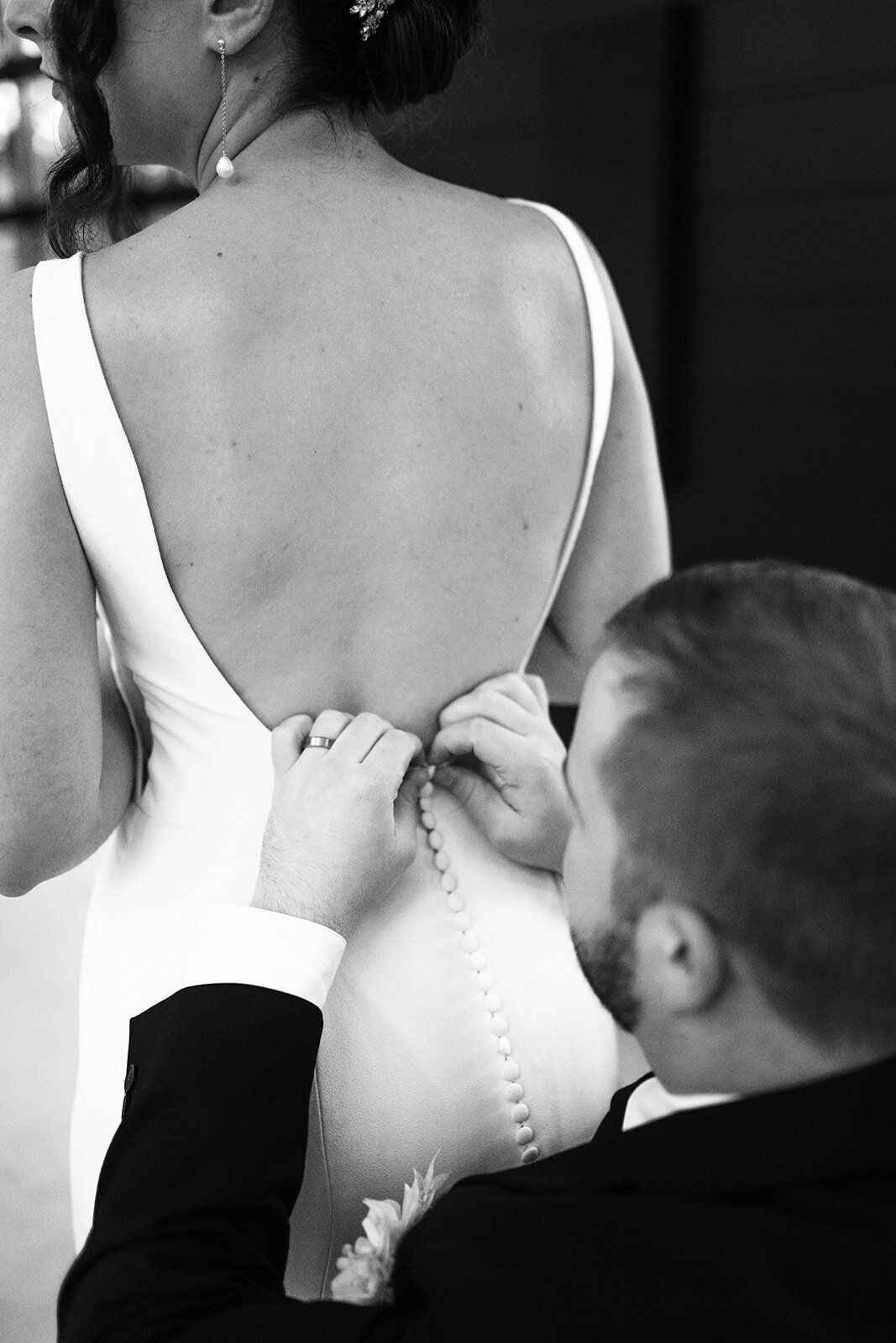 A groom buttoning the back of a bride's dress at a styled photo shoot at Sage and Social.