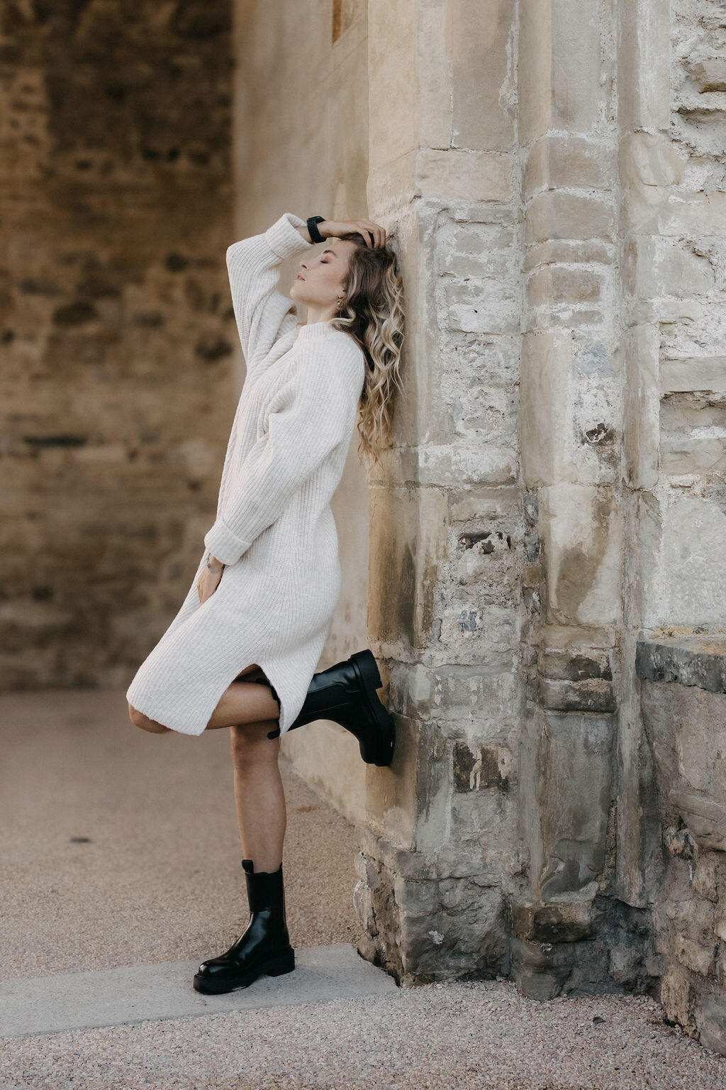 Personal Branding Portrait einer Frau im hellen Kleid an einer Steinmauer

