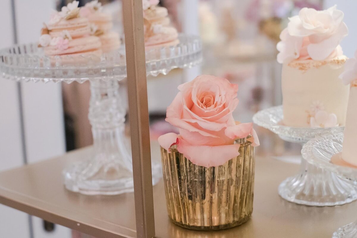 Dessert table decorated with a gold votive with a pink rose