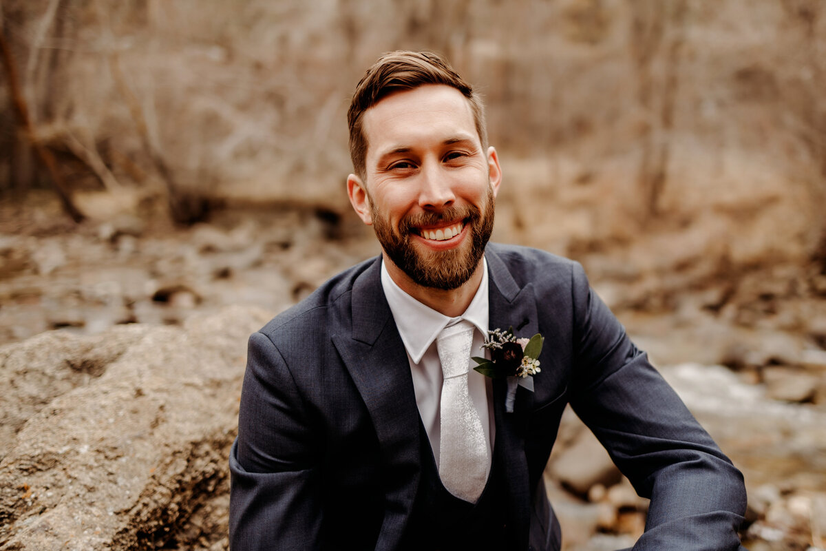 Groom sitting on large portrait outdoors at a Denver wedding venue