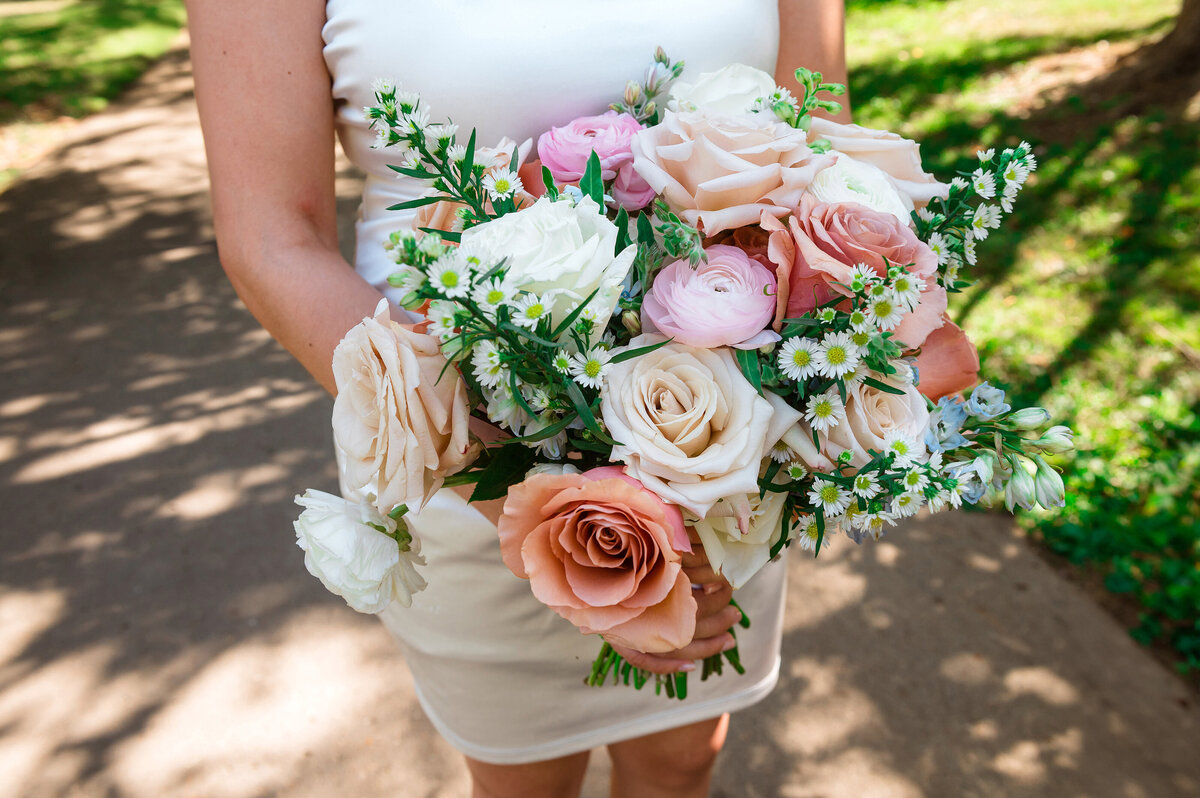 Bride holding peach and pink bouquet