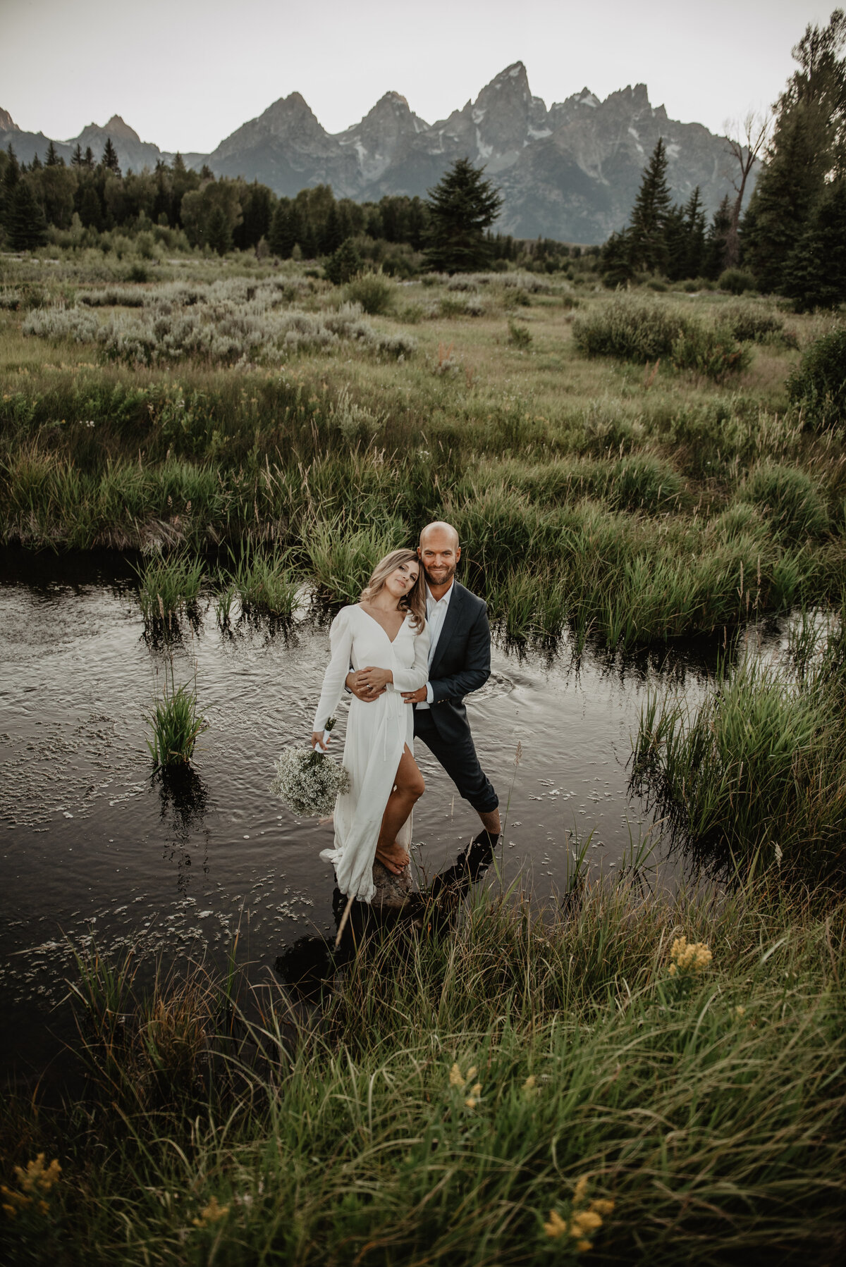 Adventure elopement session with a bride and groom standing the water of a creek holding each other