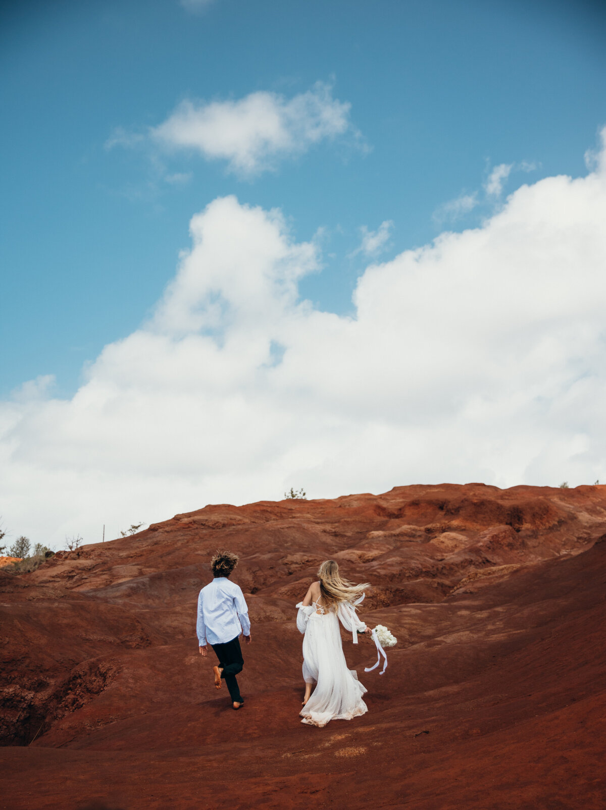 Maui Wedding Photographer captures bride and groom walking on red sand beach