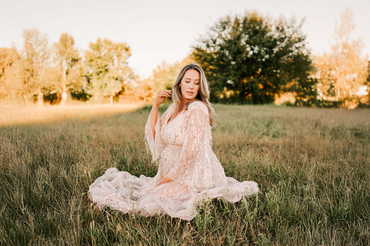 maternity photography of pregnant mom kneeling in field in Springfield MO