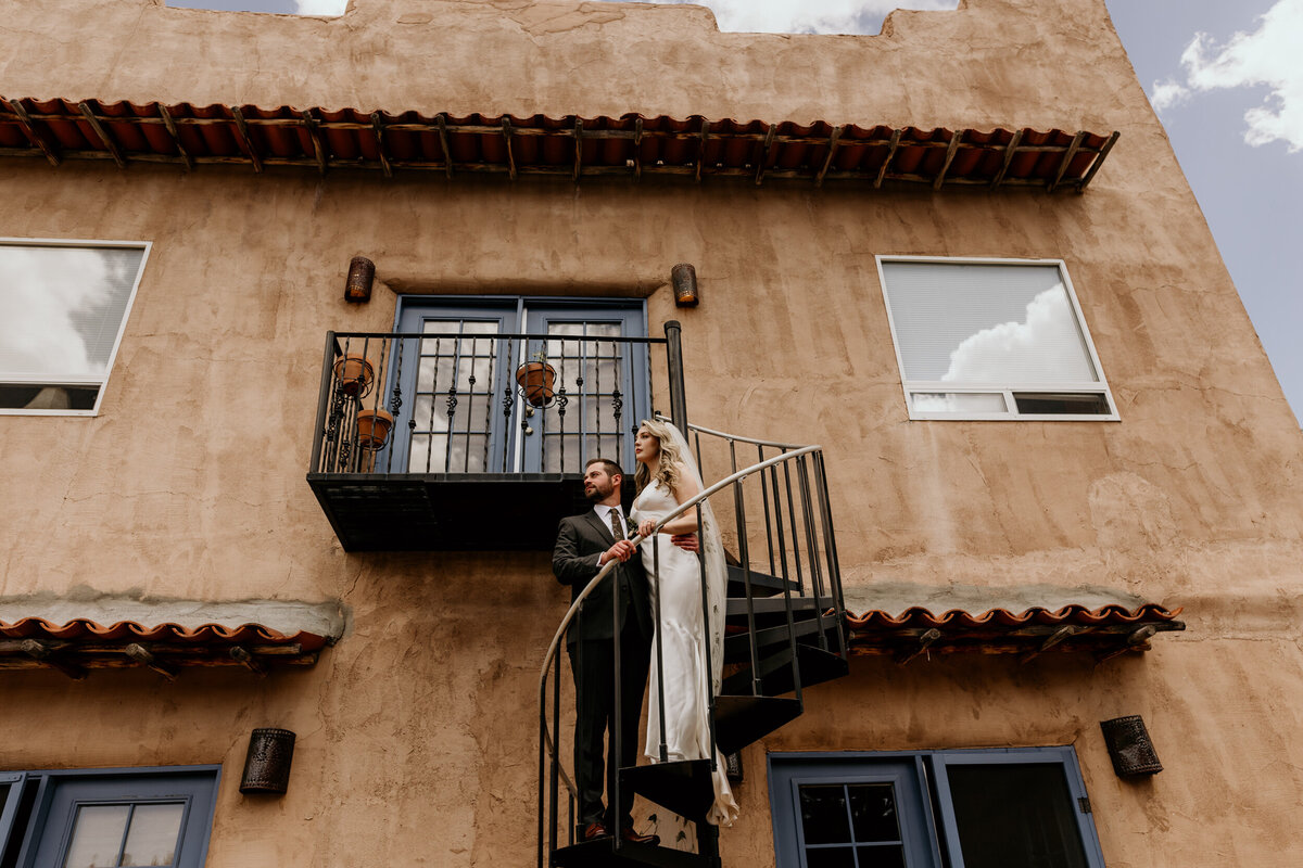 bride and groom standing on a spiral staircase together on a southwestern adobe home
