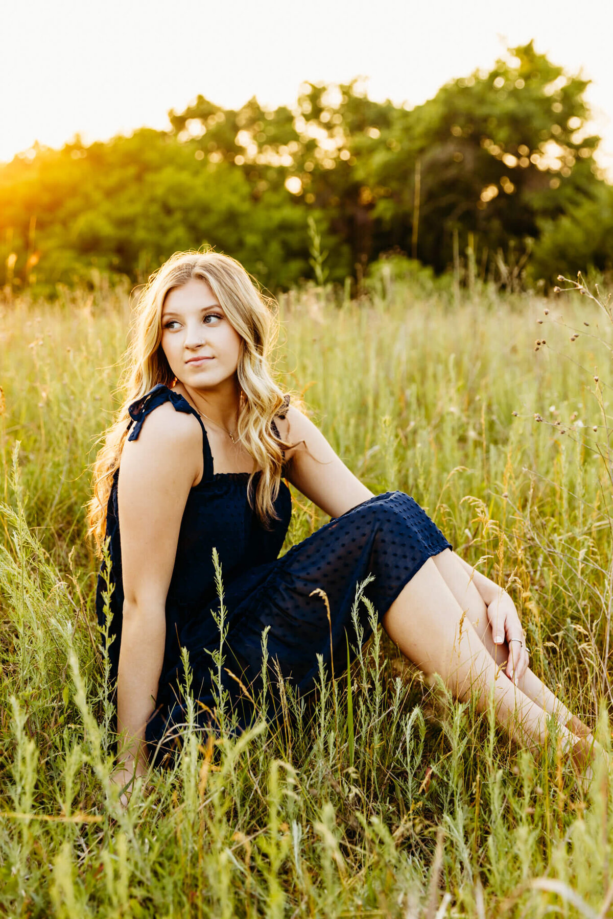 blonde high school girl in a blue dress looking over shoulder during her senior photo session