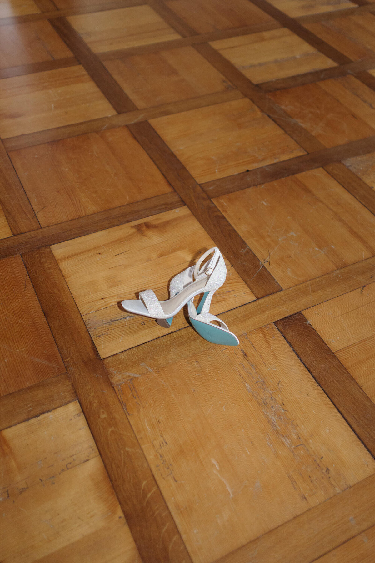 Brautschuhe auf Holzparkett – liebevolles Detail einer Hochzeit im Palast Hohenems.

