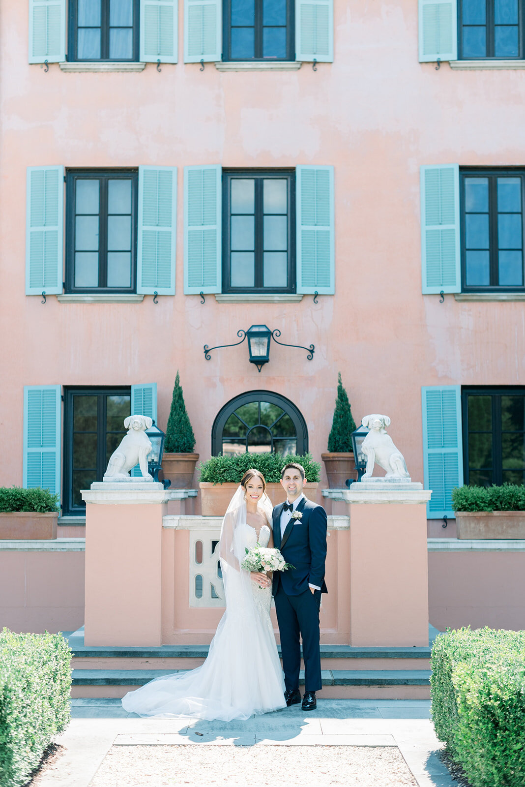 Newlyweds stand together smiling in a garden patio