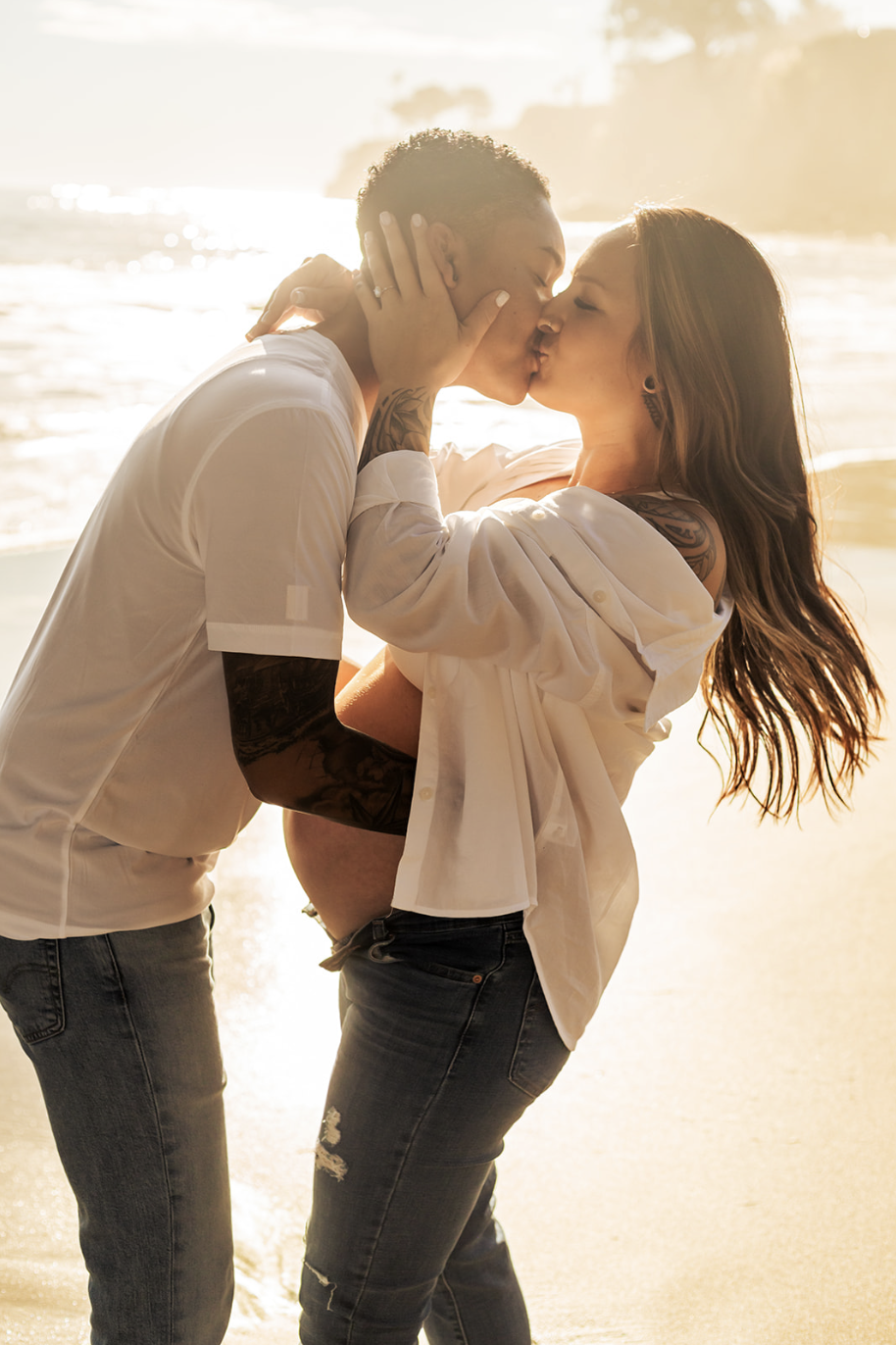 a lesbian couple kisses at their beach maternity photoshoot