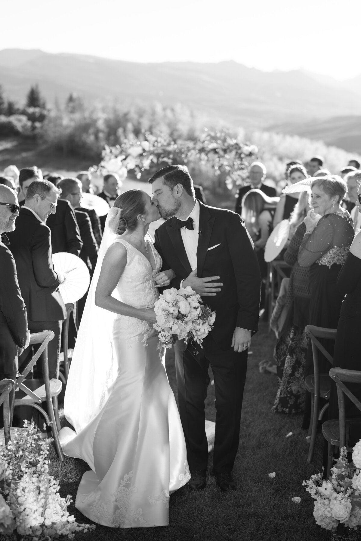 Bride and groom kiss down the aisle in Aspen