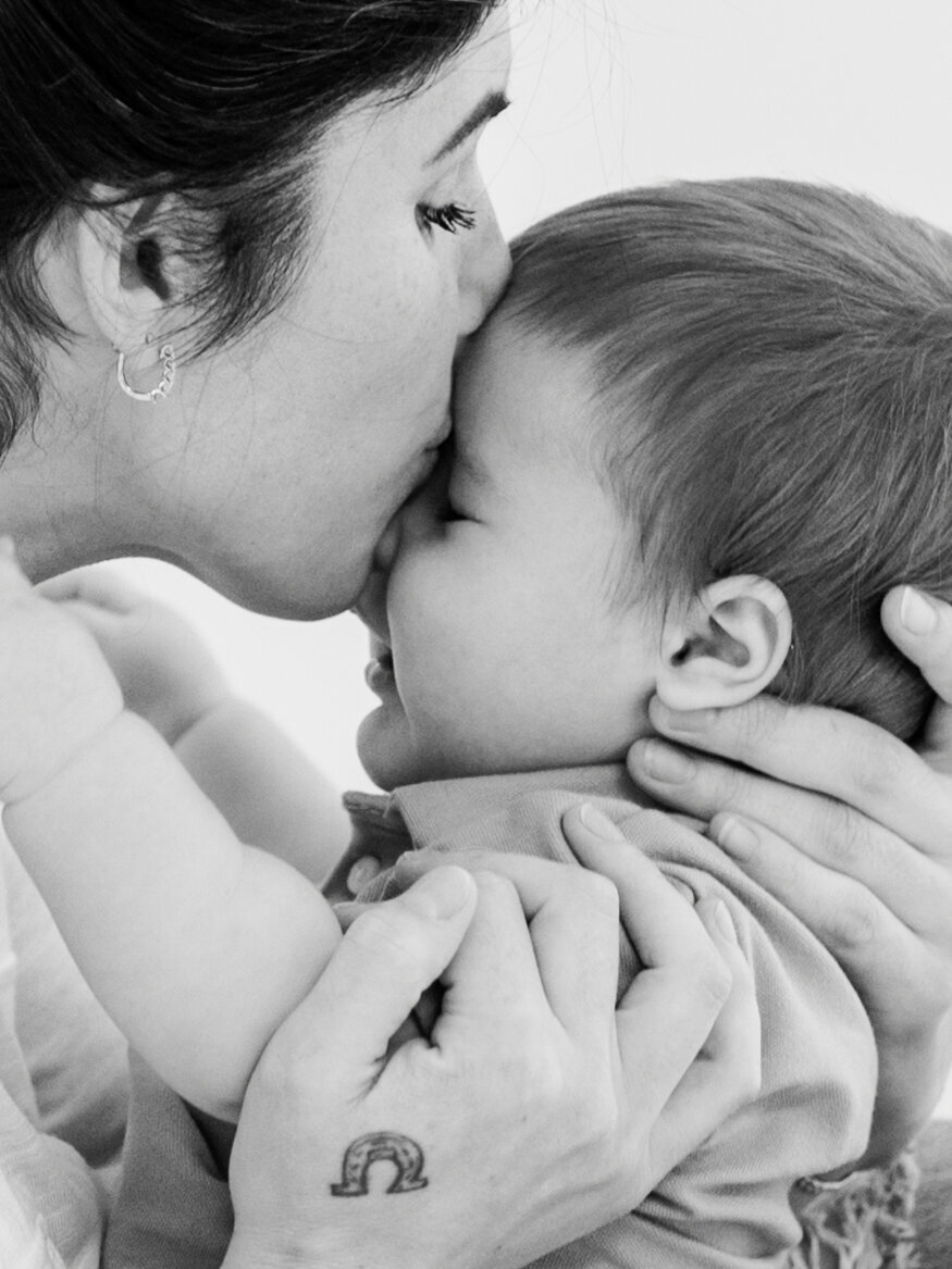 Black-and-white milestone photo of a mom kissing her baby in Bainbridge, capturing a sweet, timeless moment, serving Tallahassee area 