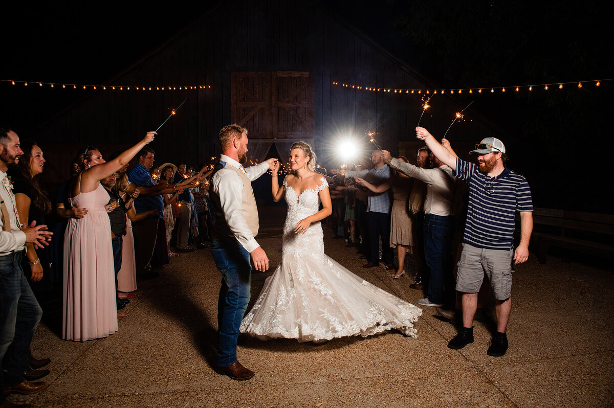 Husband spinning his wife, her dress is flaring out during their sparkler exit