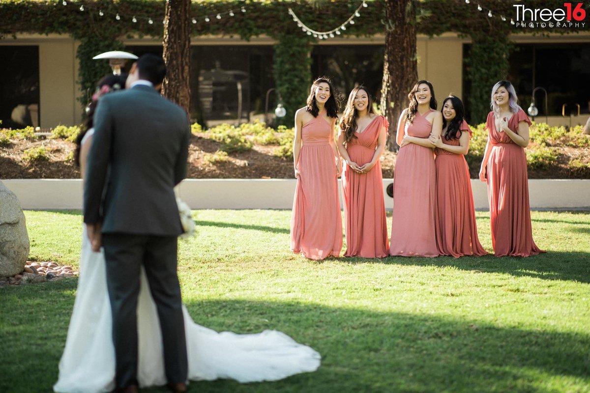 Bridesmaids are all smiles as they watch the Bride and Groom pose for photos