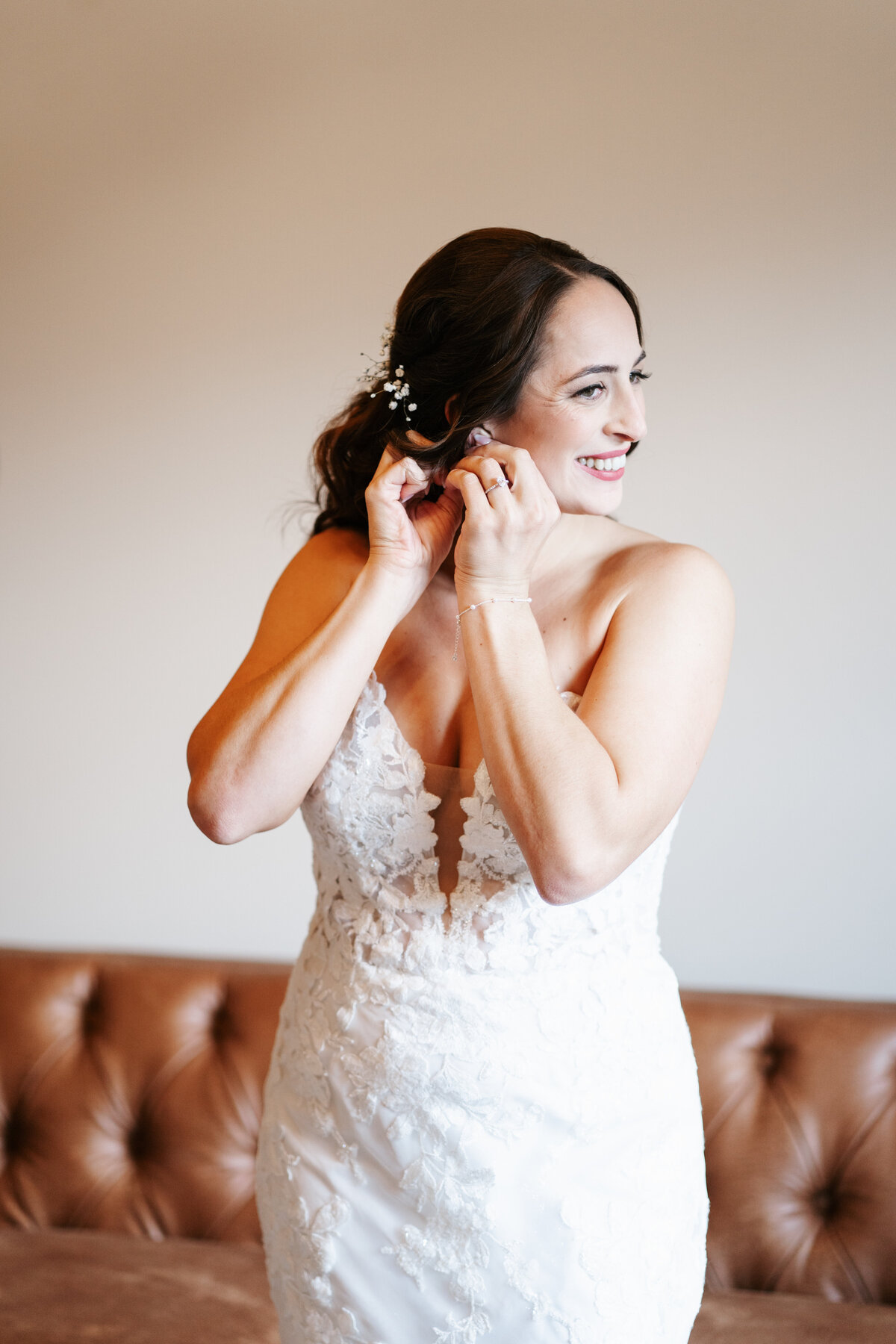 Bride putting on earrings in soft window light before her New England wedding