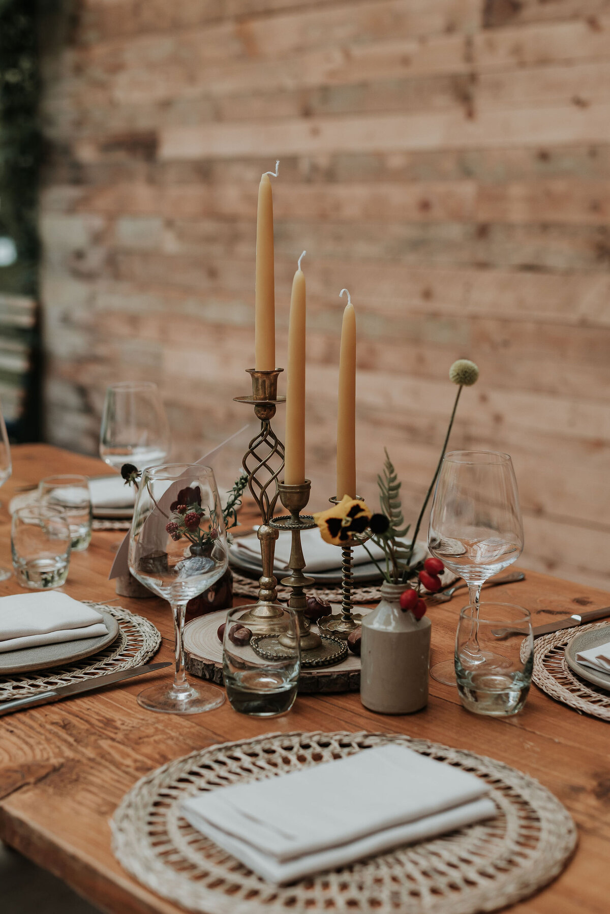 Dreamy woodland wedding tablescape with beeswax candles in brass candle sticks & wild woodland flowers along a rustic wooden table at Two Woods Estate, Pulborough