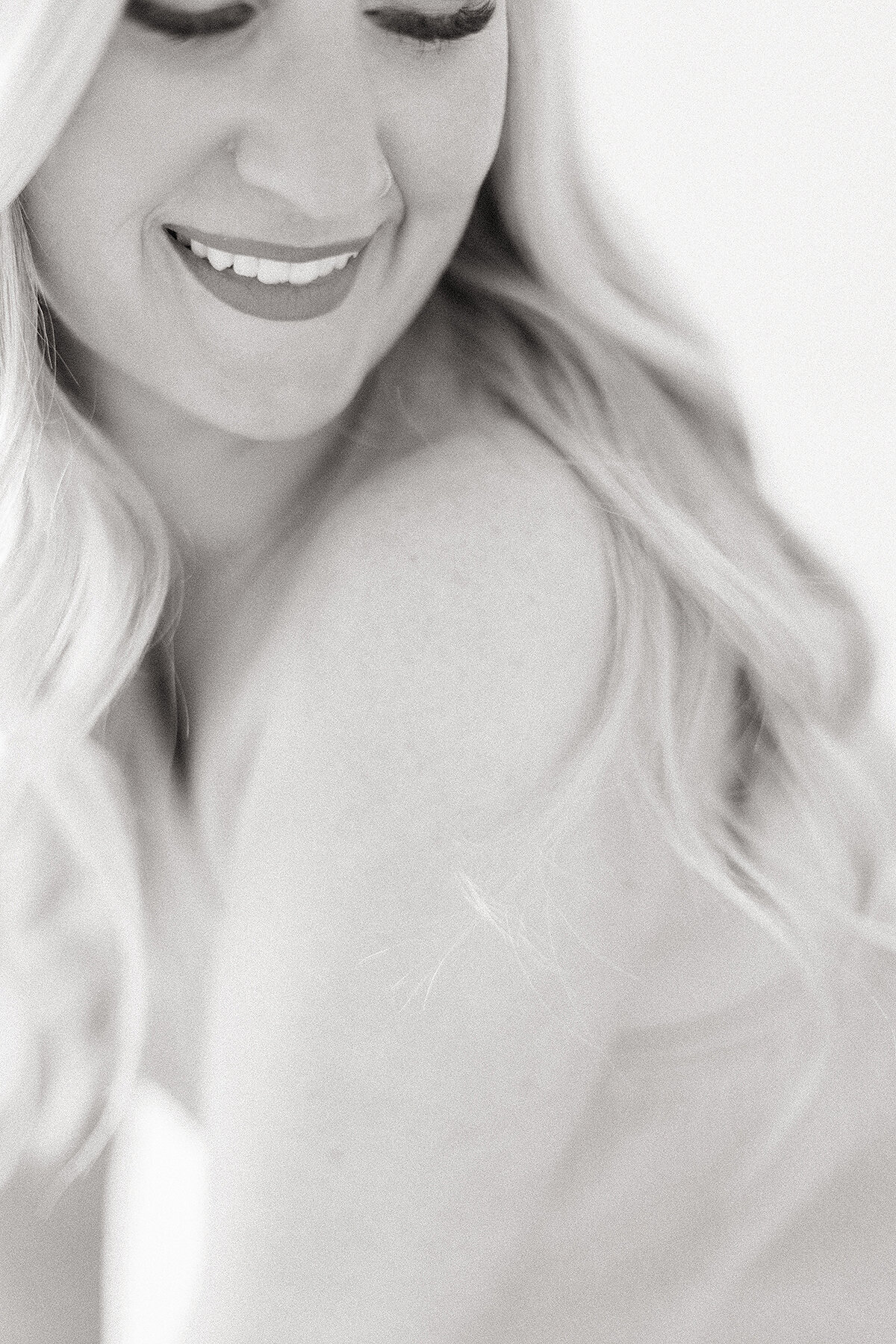 Close up elegant black and white boudoir portrait of a woman smiling and looking over her shoulder.