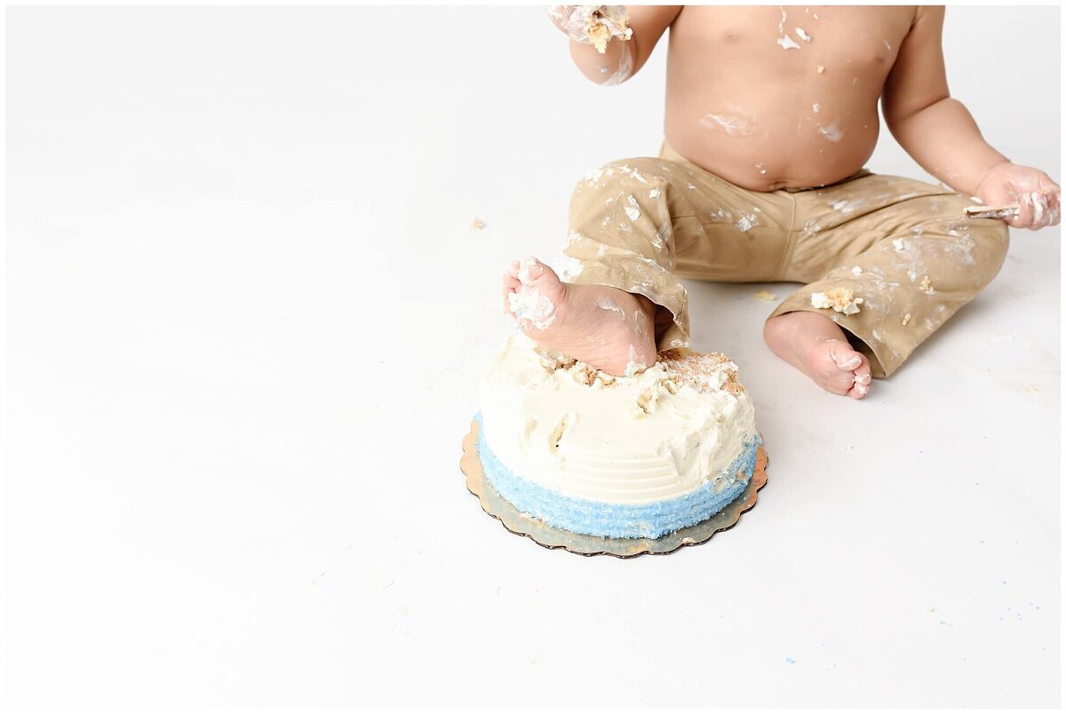 A sweet and messy cake smash session with toddler foot in cake.