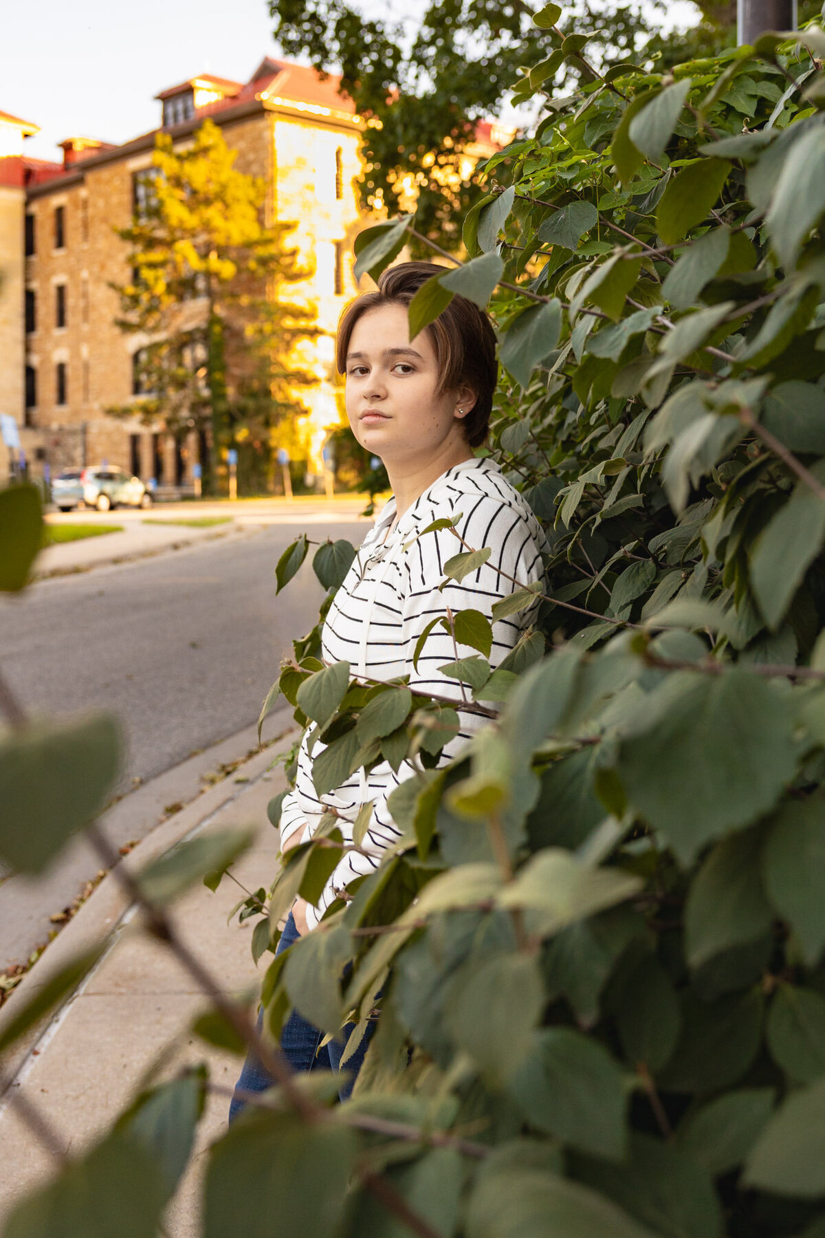 A senior girl leaning against a wall of ivy on the KU campus in Lawrence KS