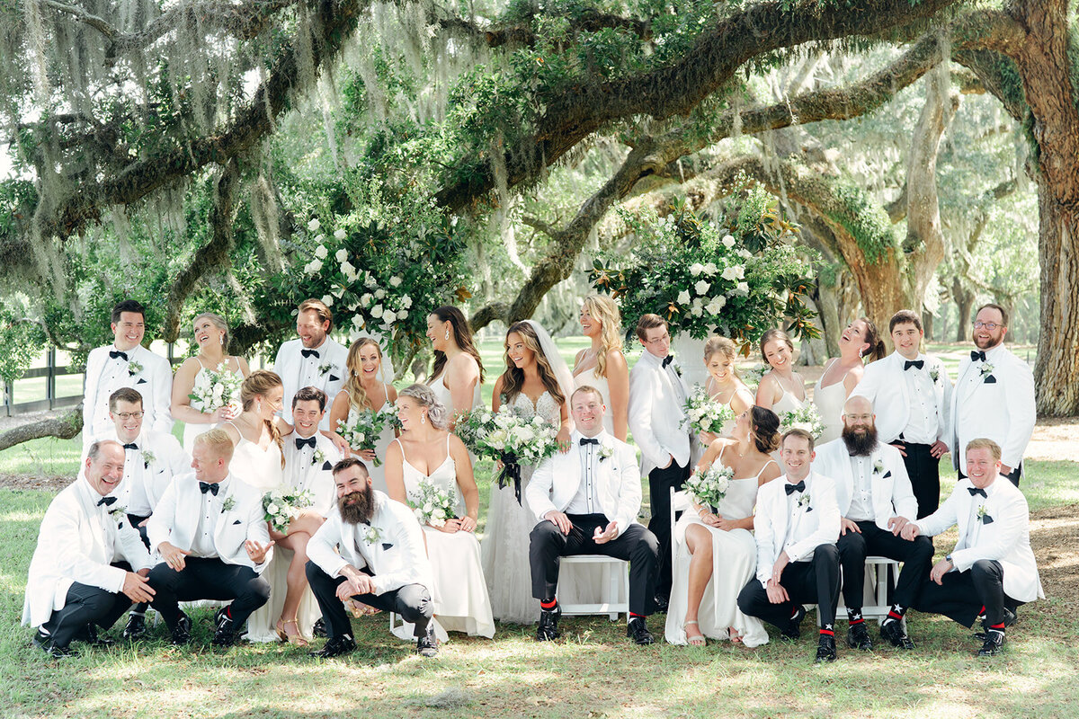 Bridesmaids and Groomsmen in white. Big group photo under the live oaks and spanish moss at Boone Hall wedding.